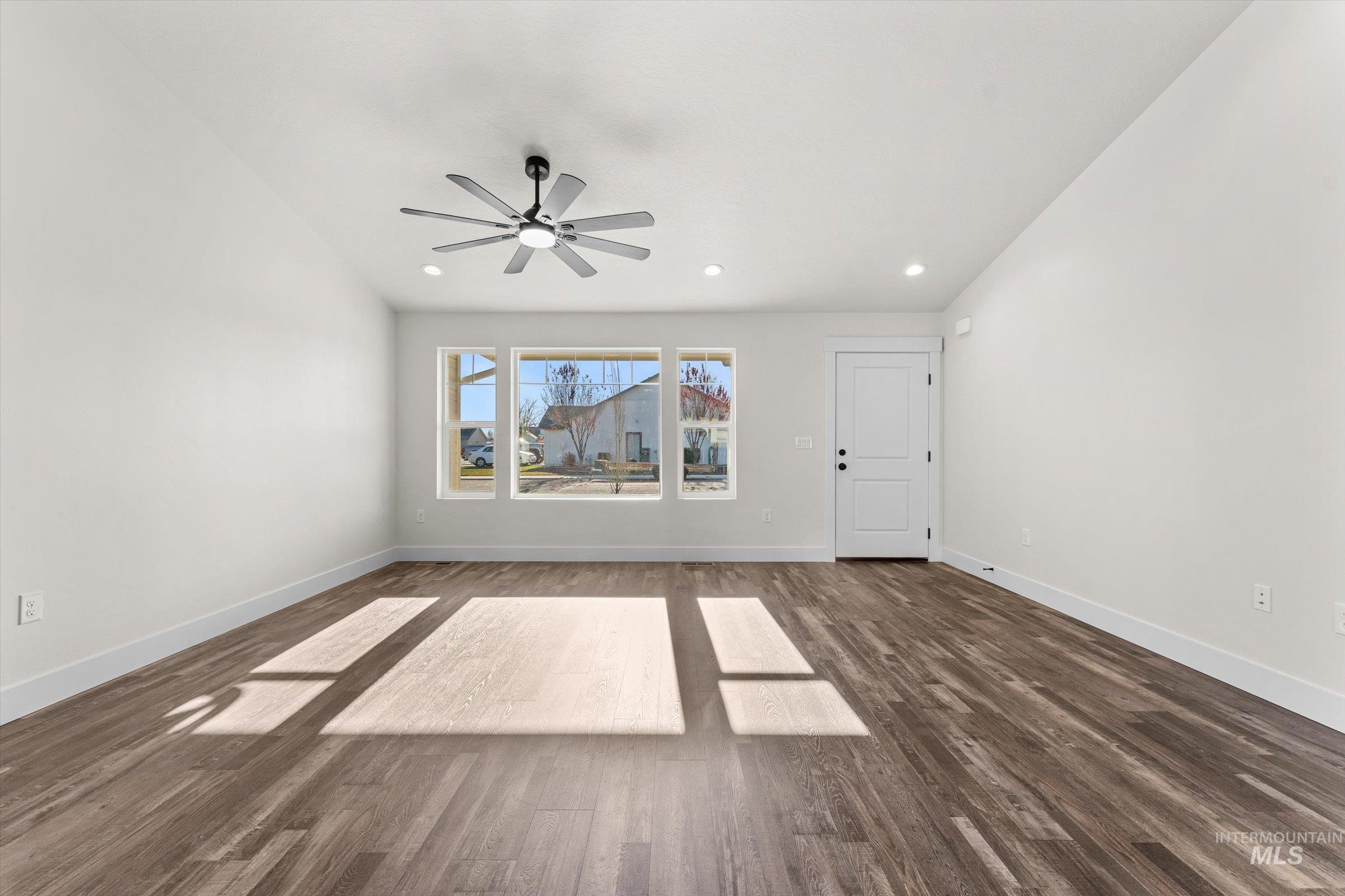 Unfurnished living room with dark wood finished floors, recessed lighting, a ceiling fan, and vaulted ceiling
