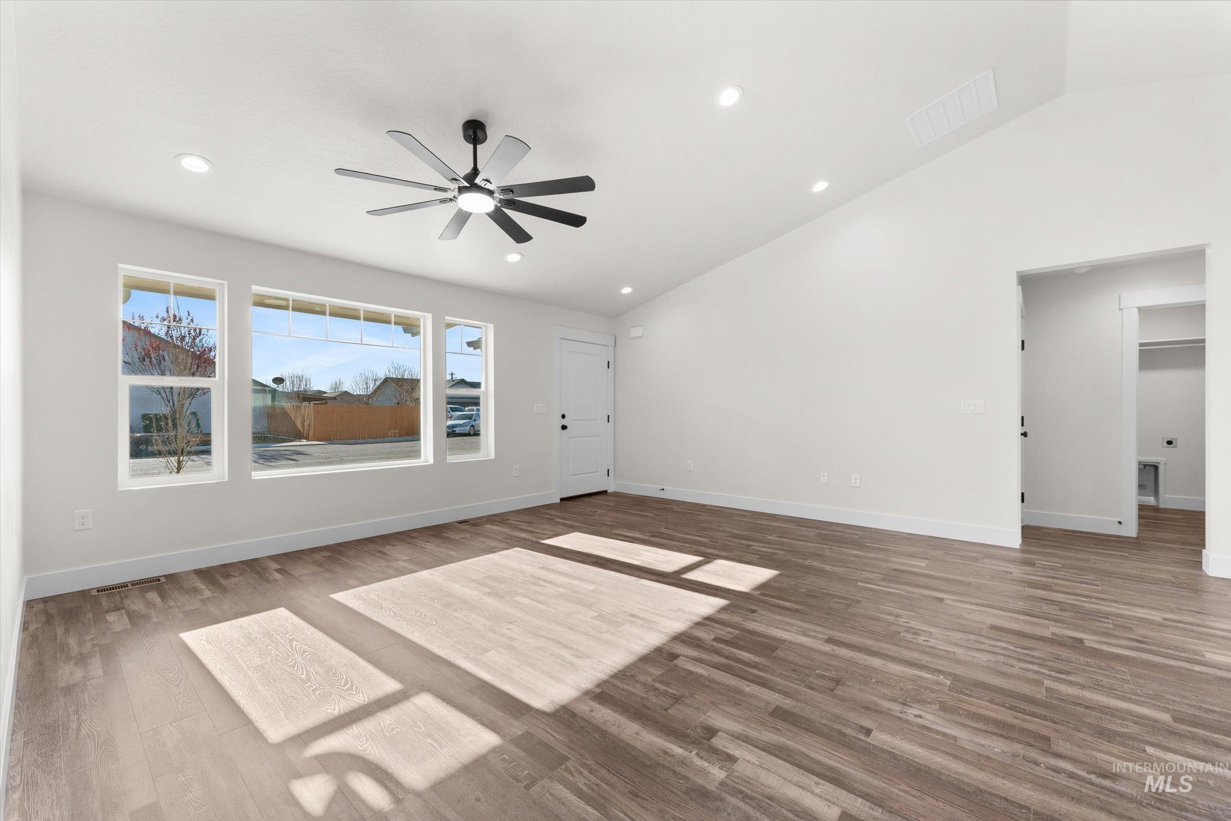Unfurnished living room with vaulted ceiling, wood finished floors, ceiling fan, and recessed lighting