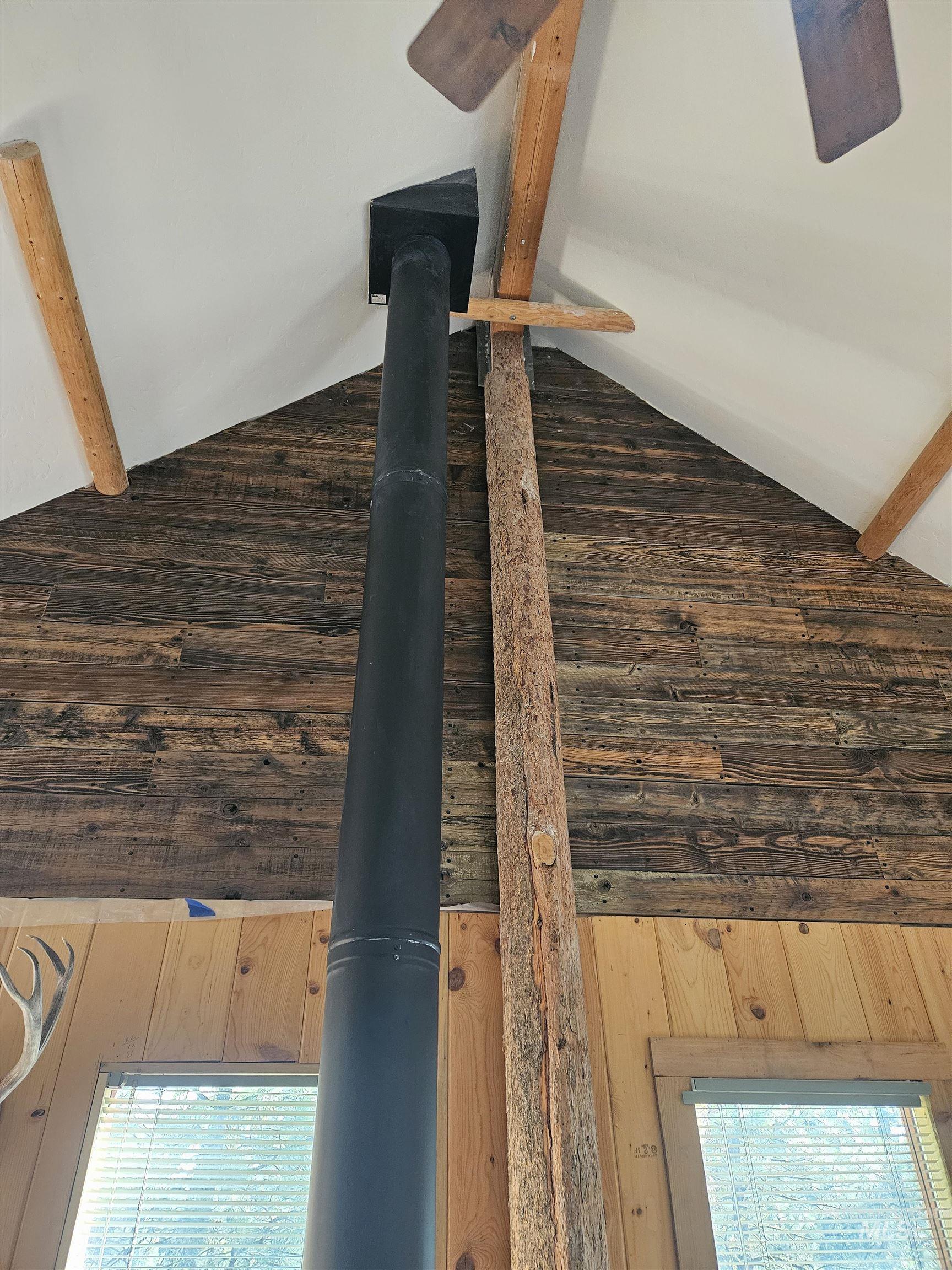Detailed view of beamed ceiling, wood walls, and a wood stove