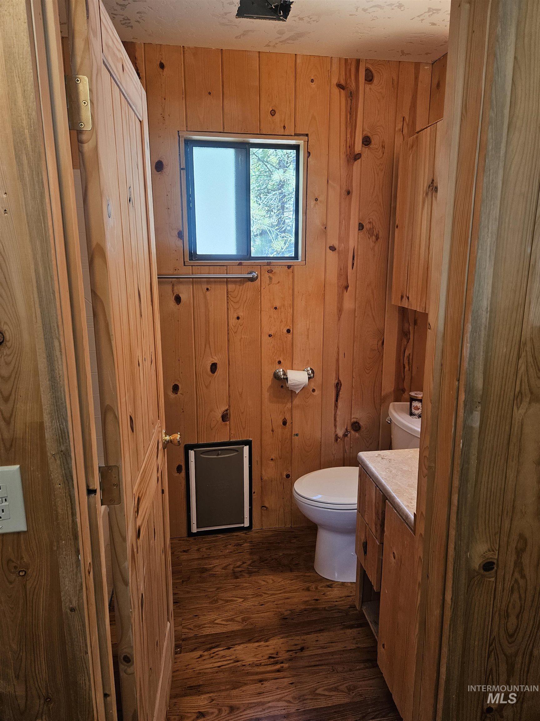 Bathroom featuring vanity, wood walls, and wood finished floors