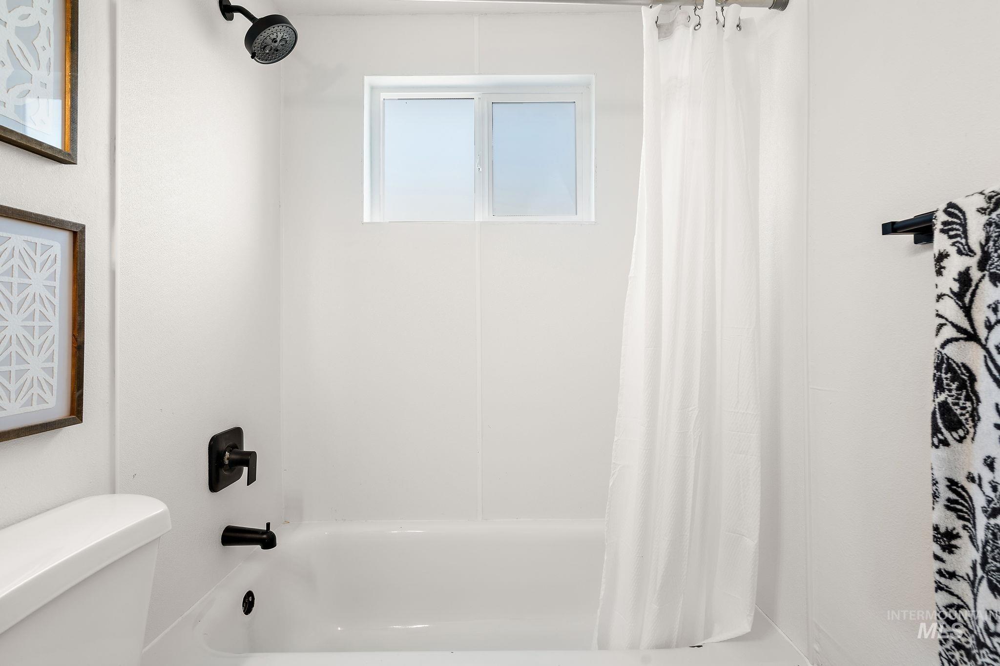 Bathroom with shower / bath combination with curtain and toilet