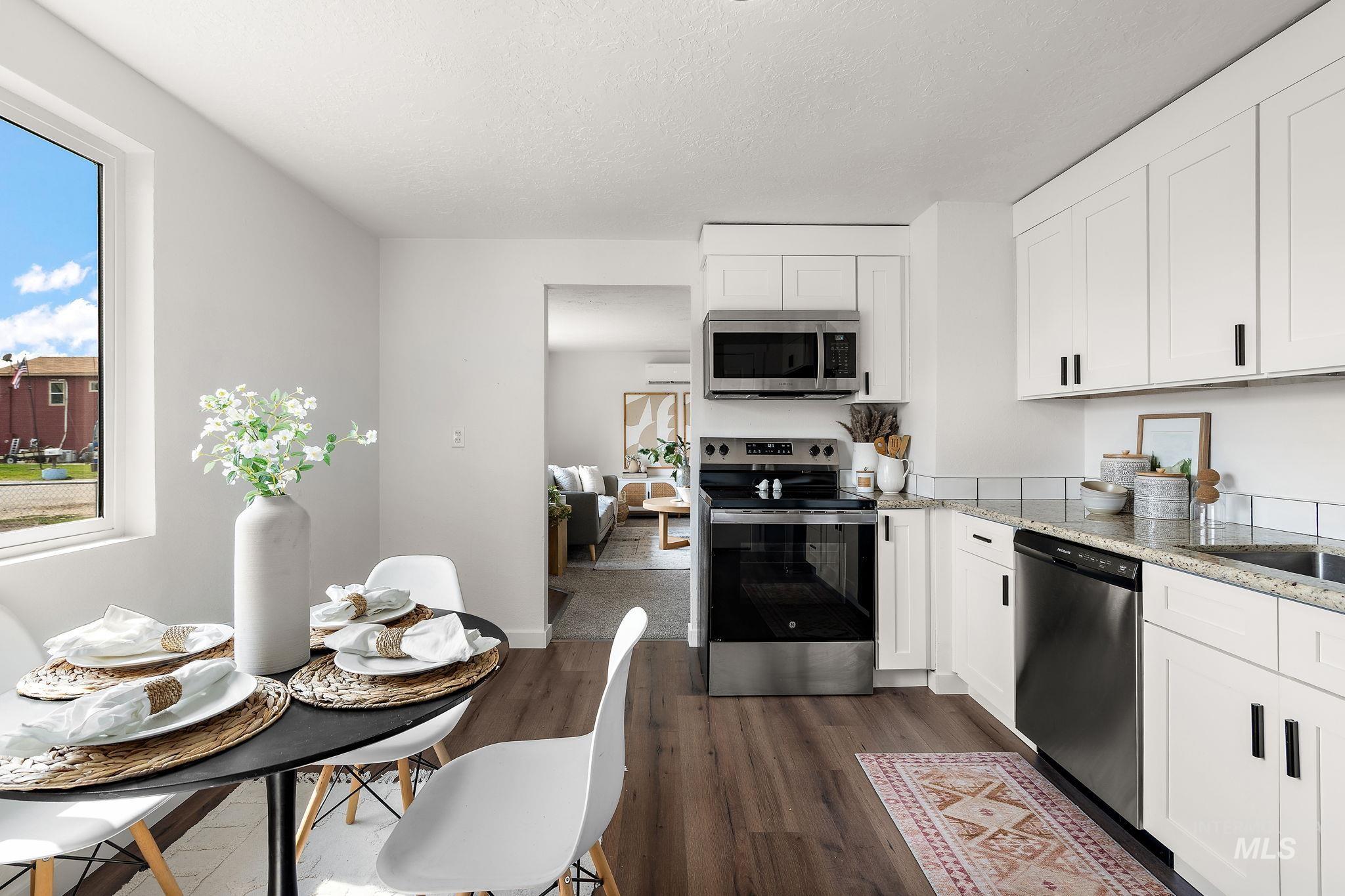 Kitchen with appliances with stainless steel finishes, white cabinets, dark wood-style floors, light stone counters, and a textured ceiling