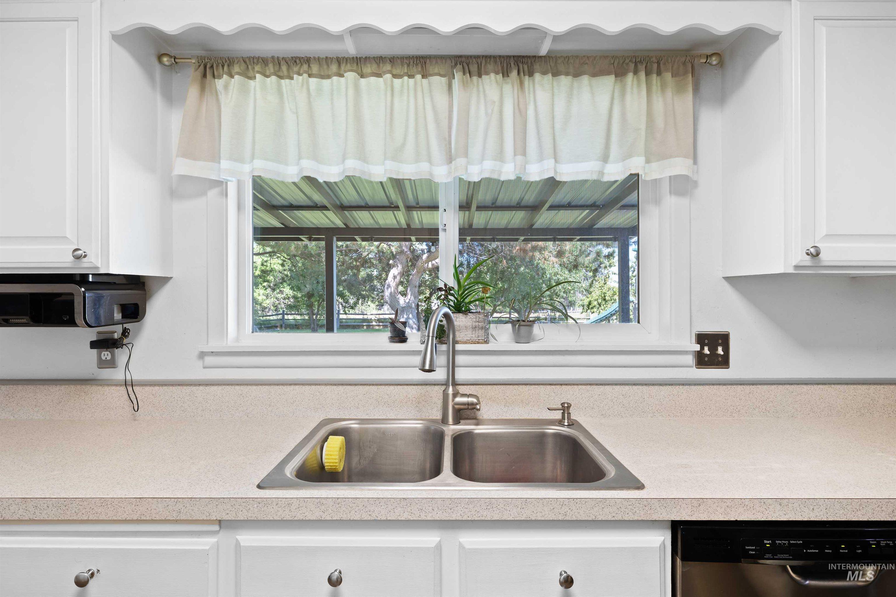 Kitchen with light countertops, white cabinets, and stainless steel dishwasher