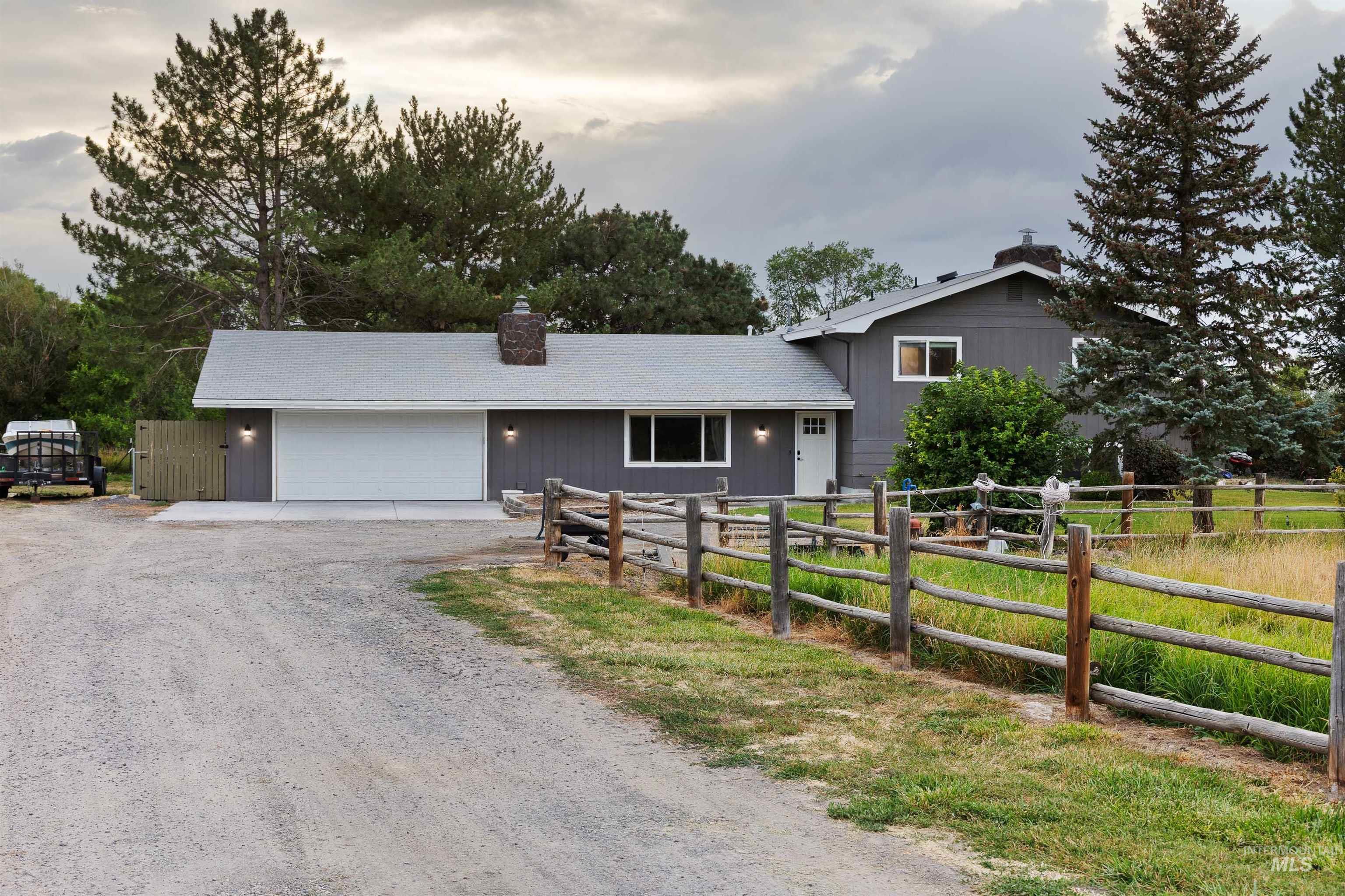 View of front of house featuring driveway, a garage, and a chimney