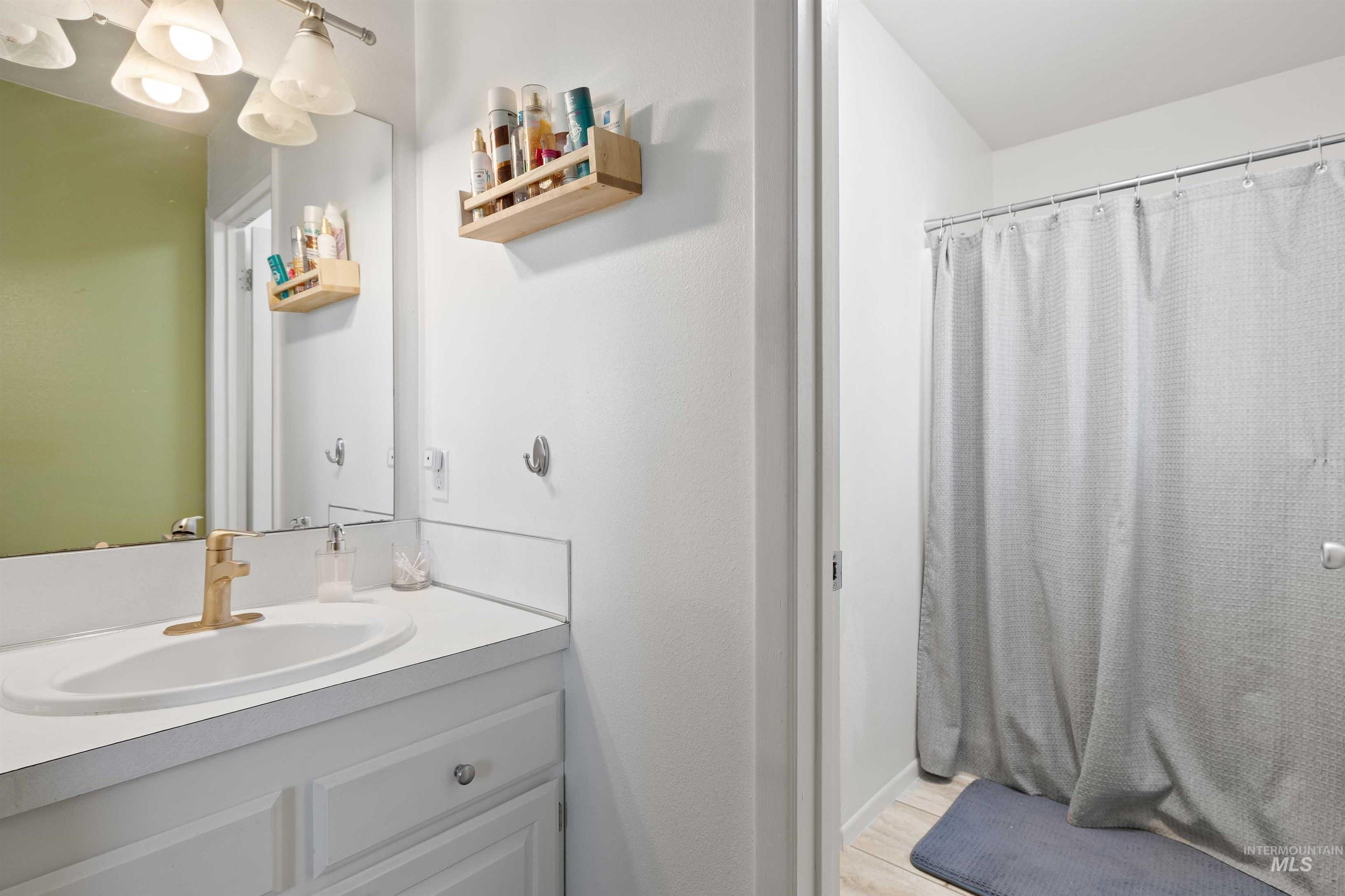 Full bathroom featuring vanity, a shower with curtain, and wood finished floors