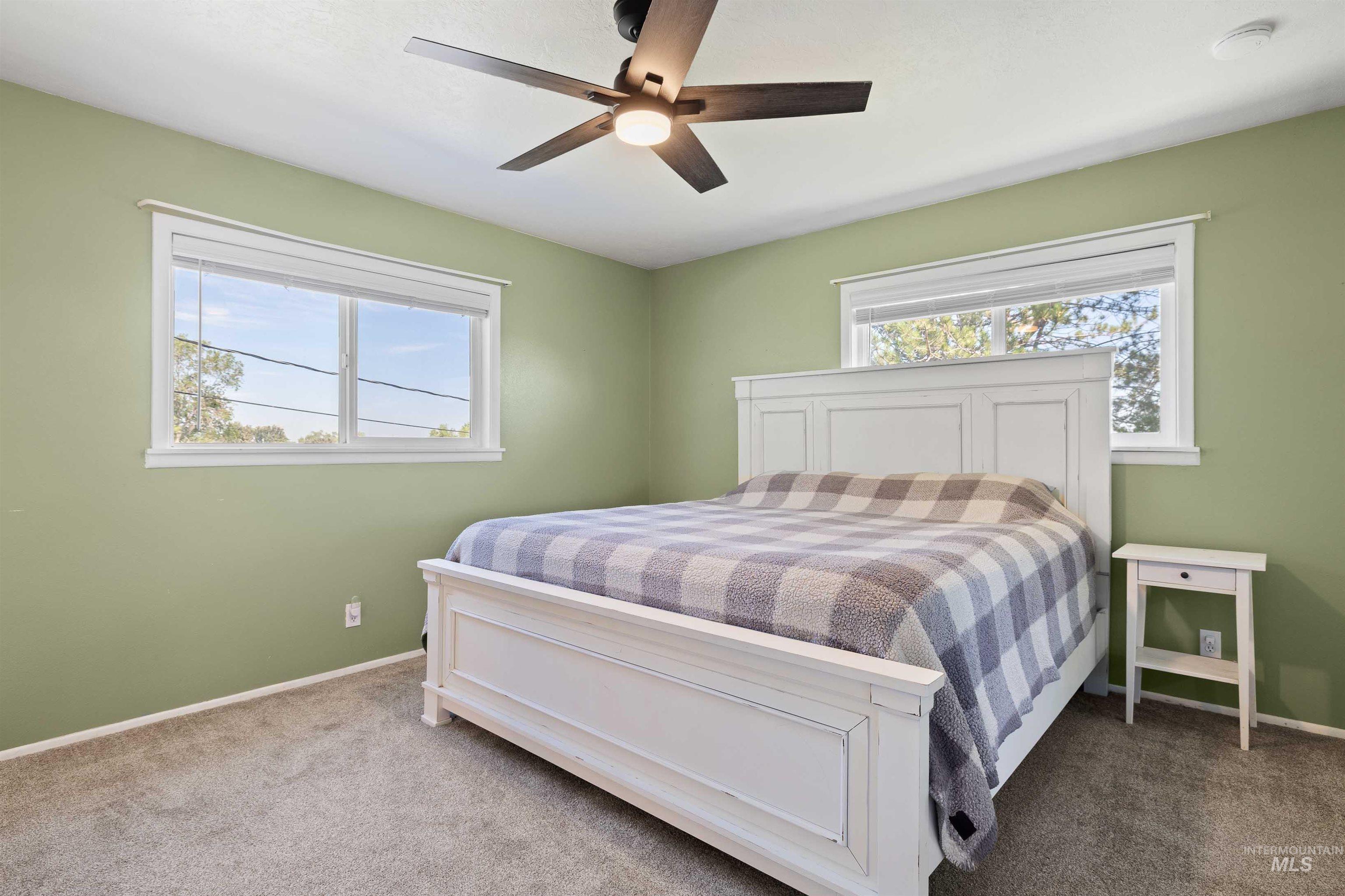 Bedroom featuring multiple windows, carpet flooring, and a ceiling fan
