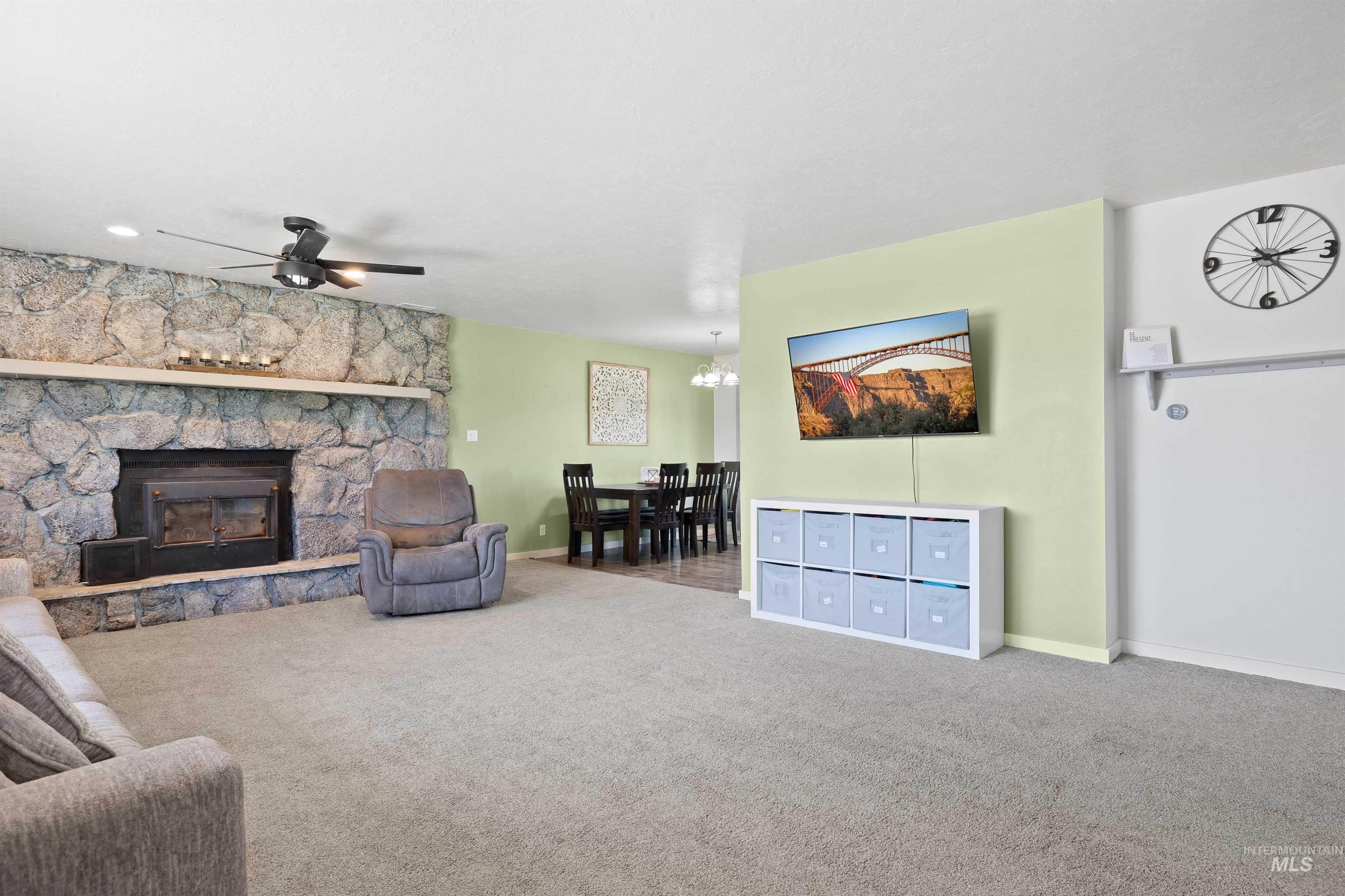 Carpeted living area featuring a ceiling fan and a fireplace