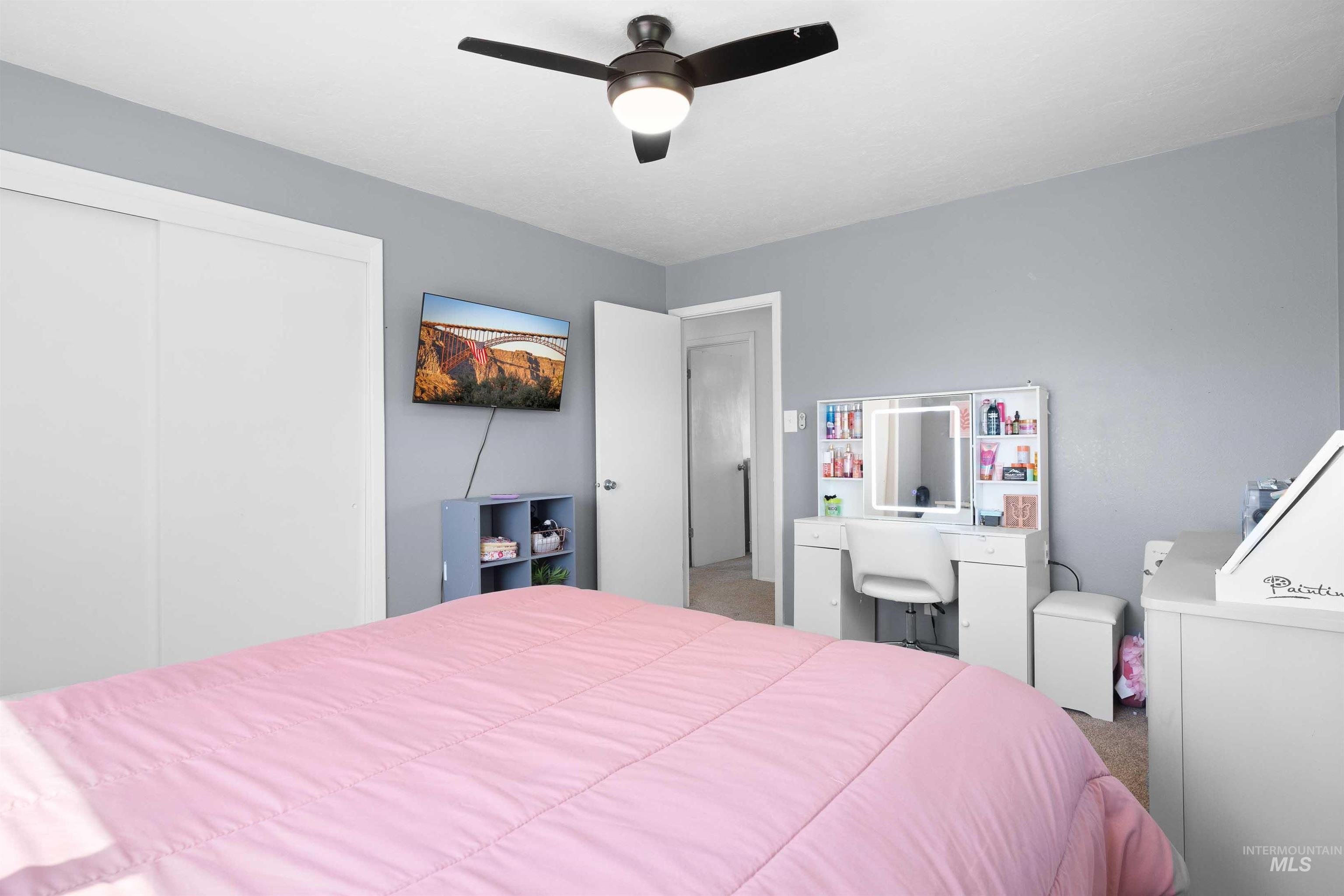 Carpeted bedroom with ceiling fan and a closet