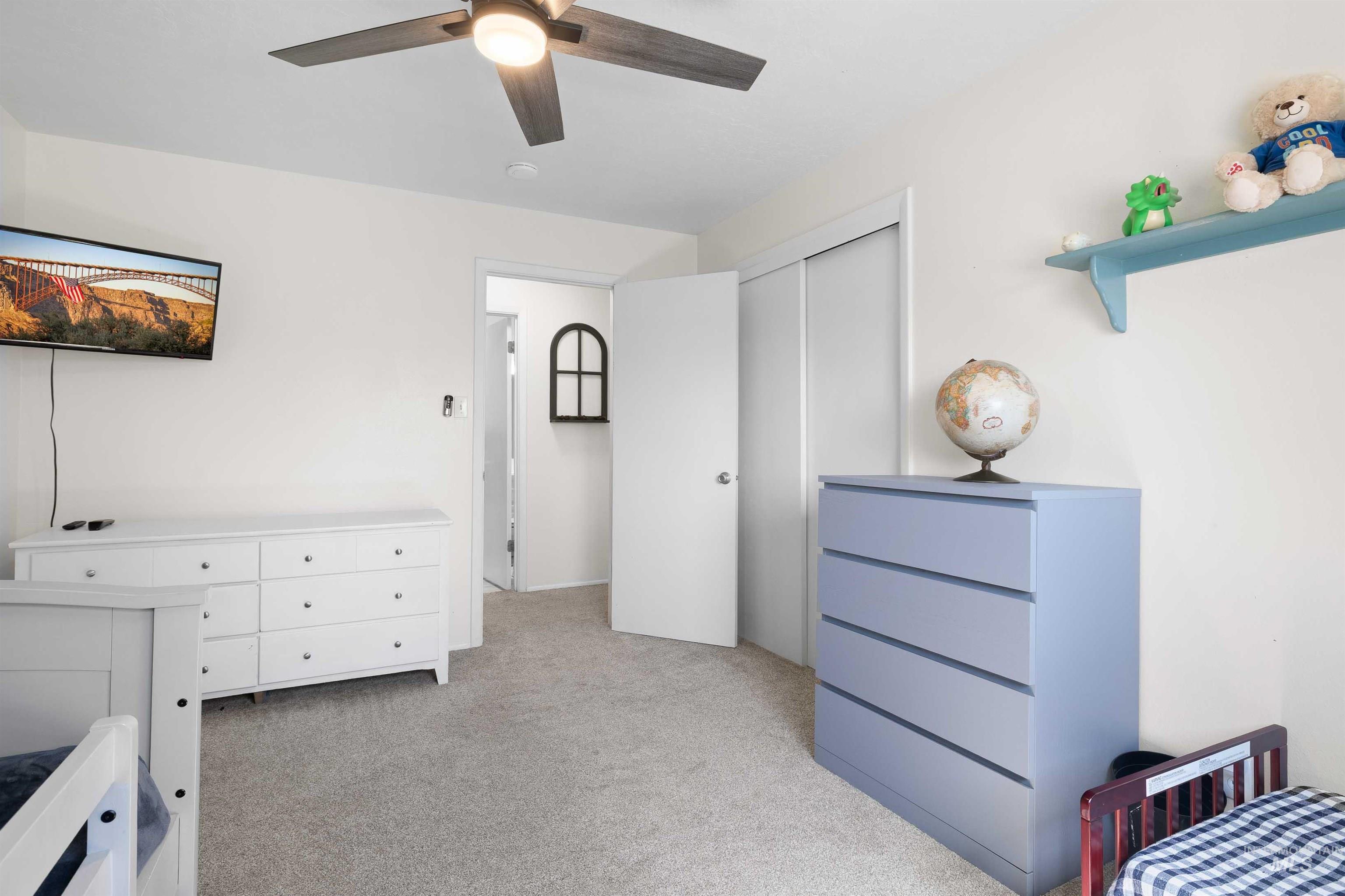 Bedroom with light colored carpet, a closet, and ceiling fan