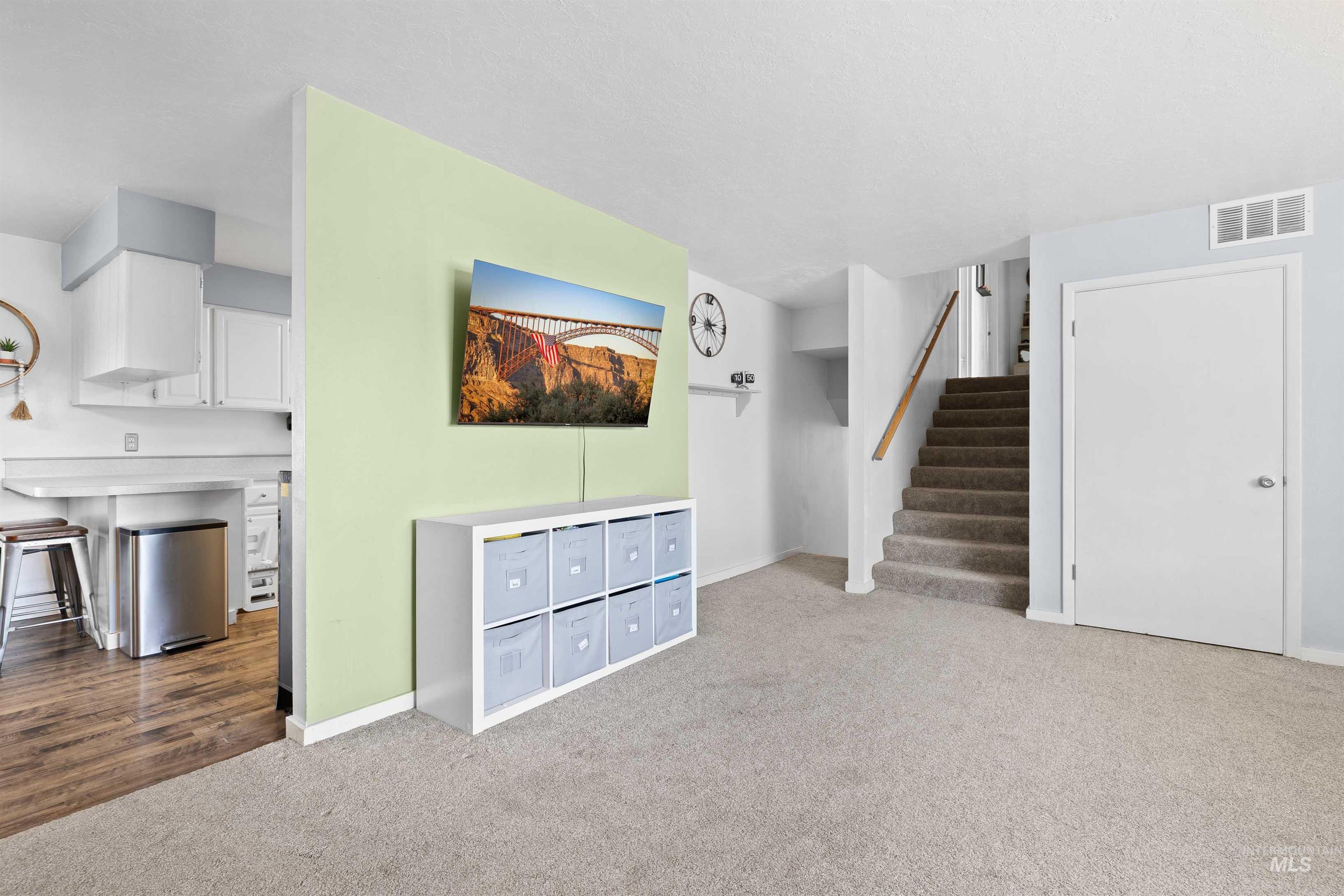 Unfurnished living room with carpet flooring and stairway