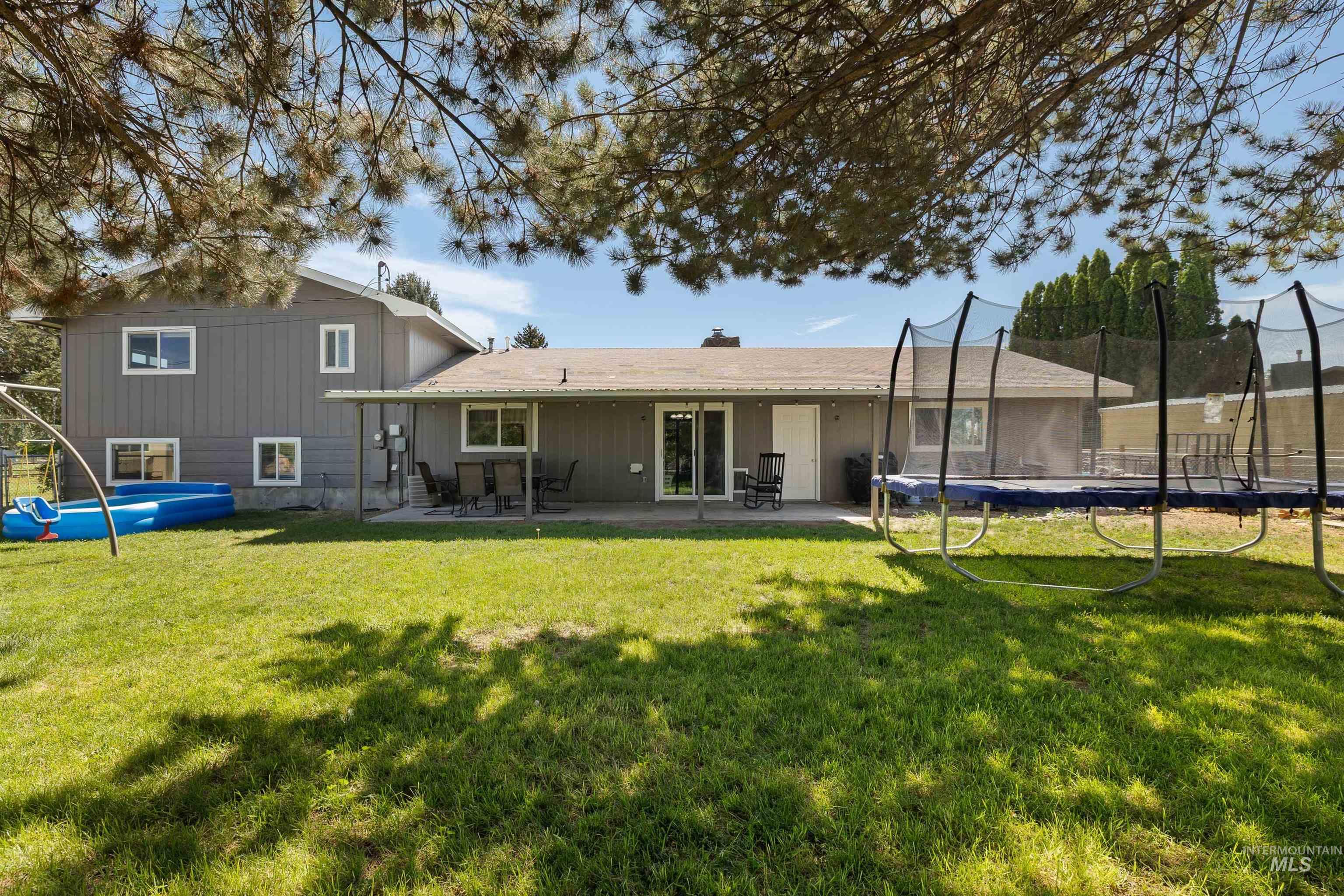 Rear view of property featuring a trampoline, a patio, a chimney, a yard, and an outdoor pool
