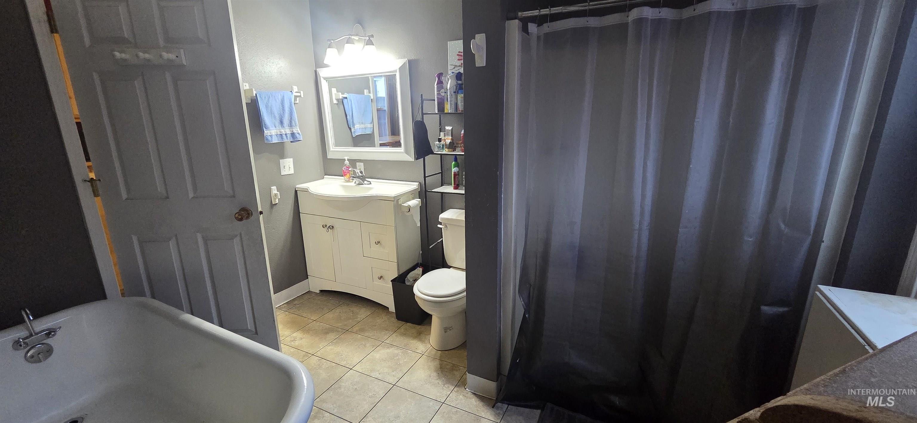Full bath featuring vanity, a shower, light tile patterned floors, and a freestanding clawfoot bath