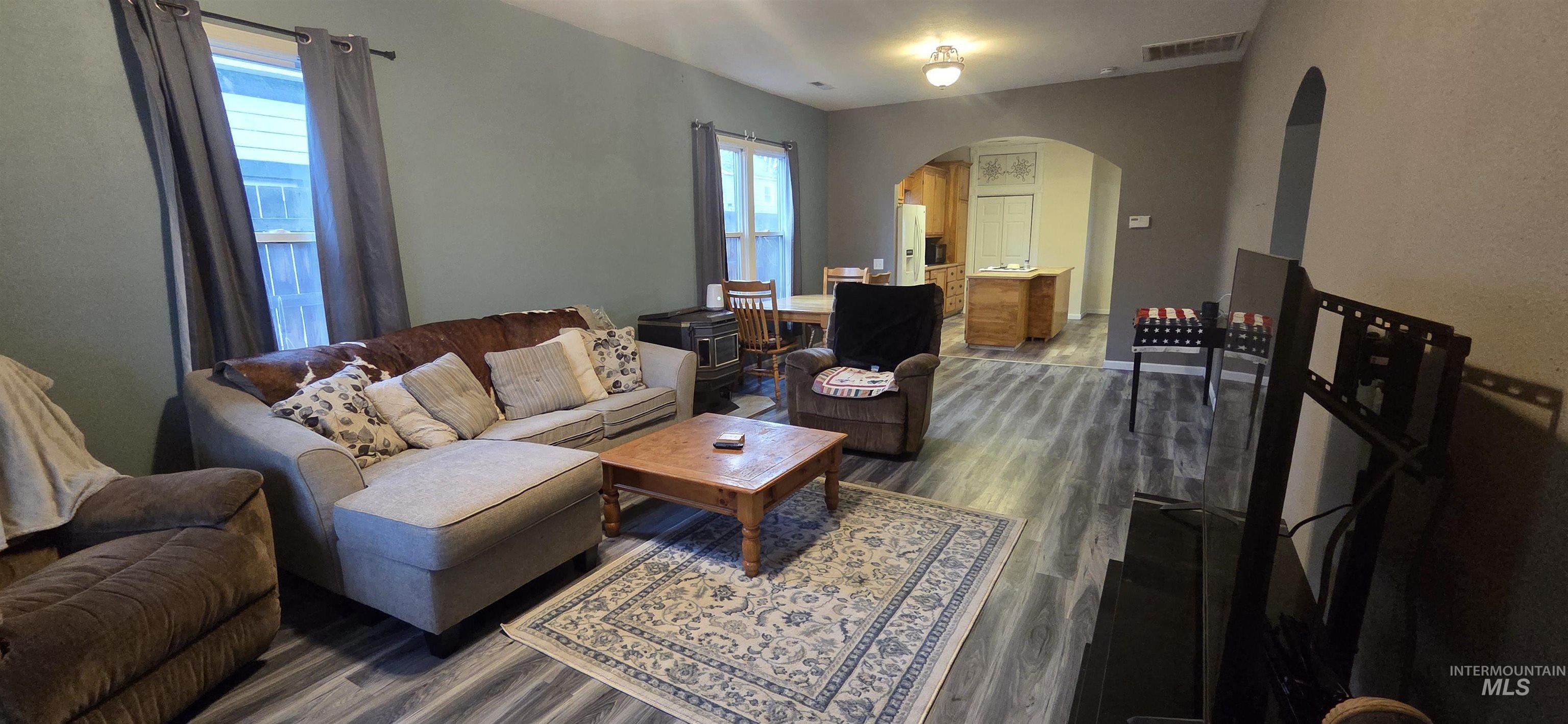 Living area featuring arched walkways and dark wood-style flooring
