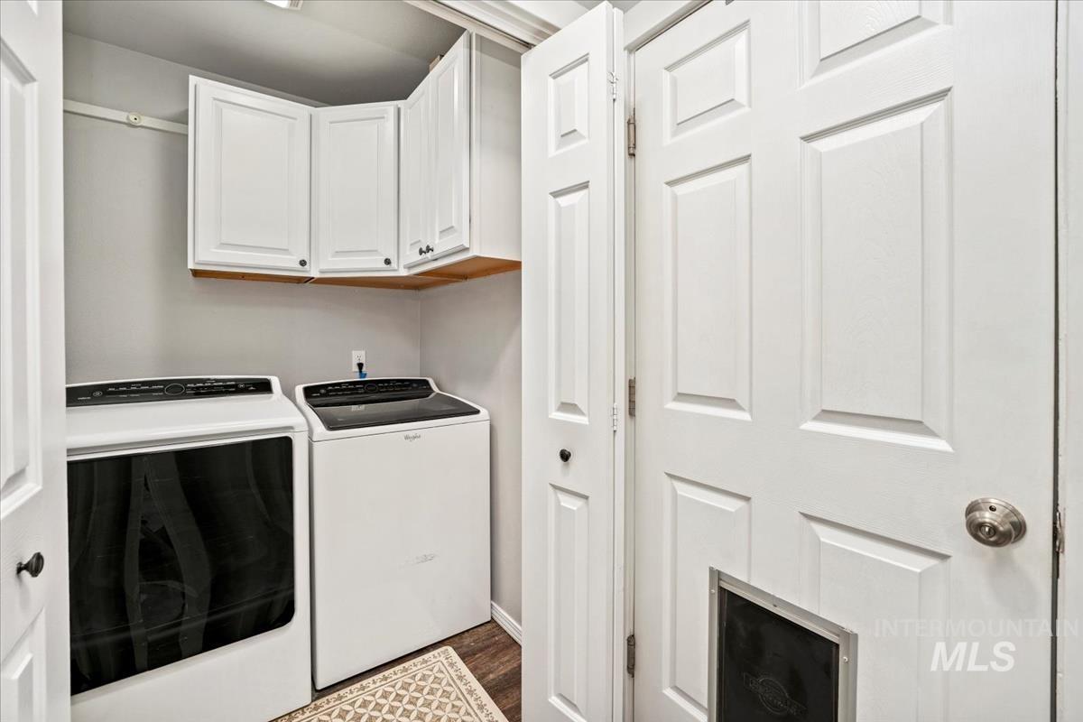 Laundry room featuring washing machine and dryer, dark wood-style flooring, and cabinet space