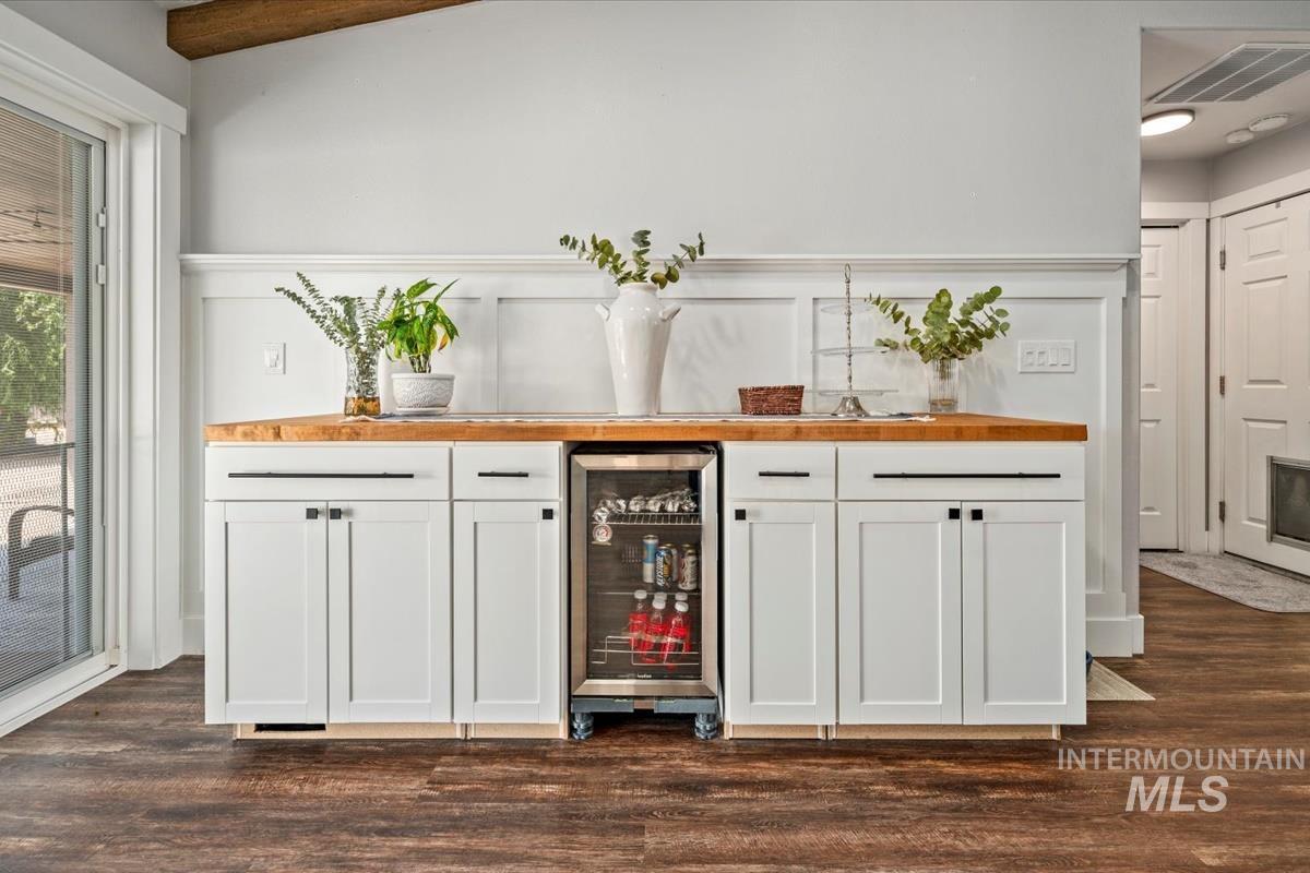 Indoor dry bar featuring wine cooler and dark wood-style floors
