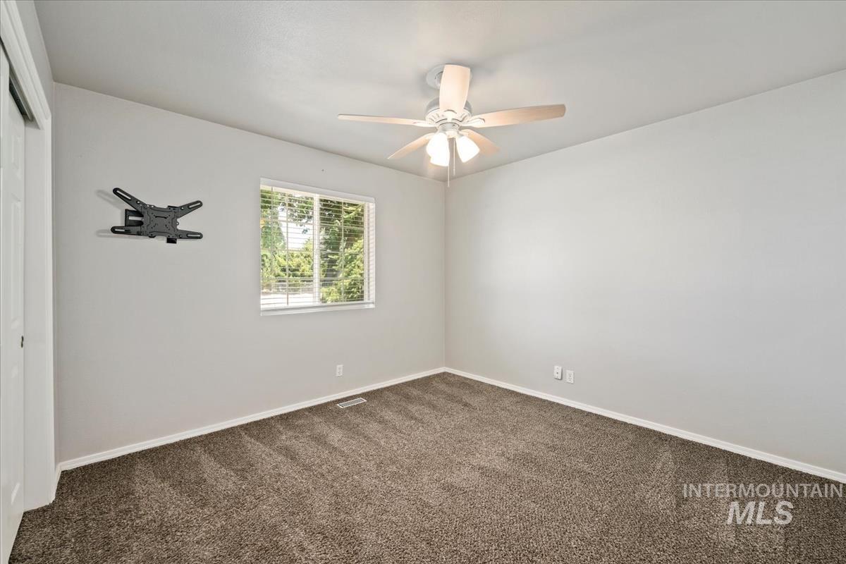 Spare room with dark carpet and a ceiling fan