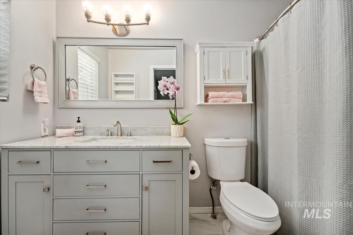 Full bathroom featuring vanity, marble look tiles, and curtained shower