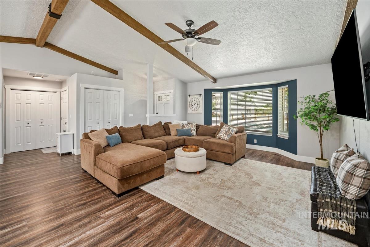 Living area featuring dark wood finished floors, a ceiling fan, and a textured ceiling