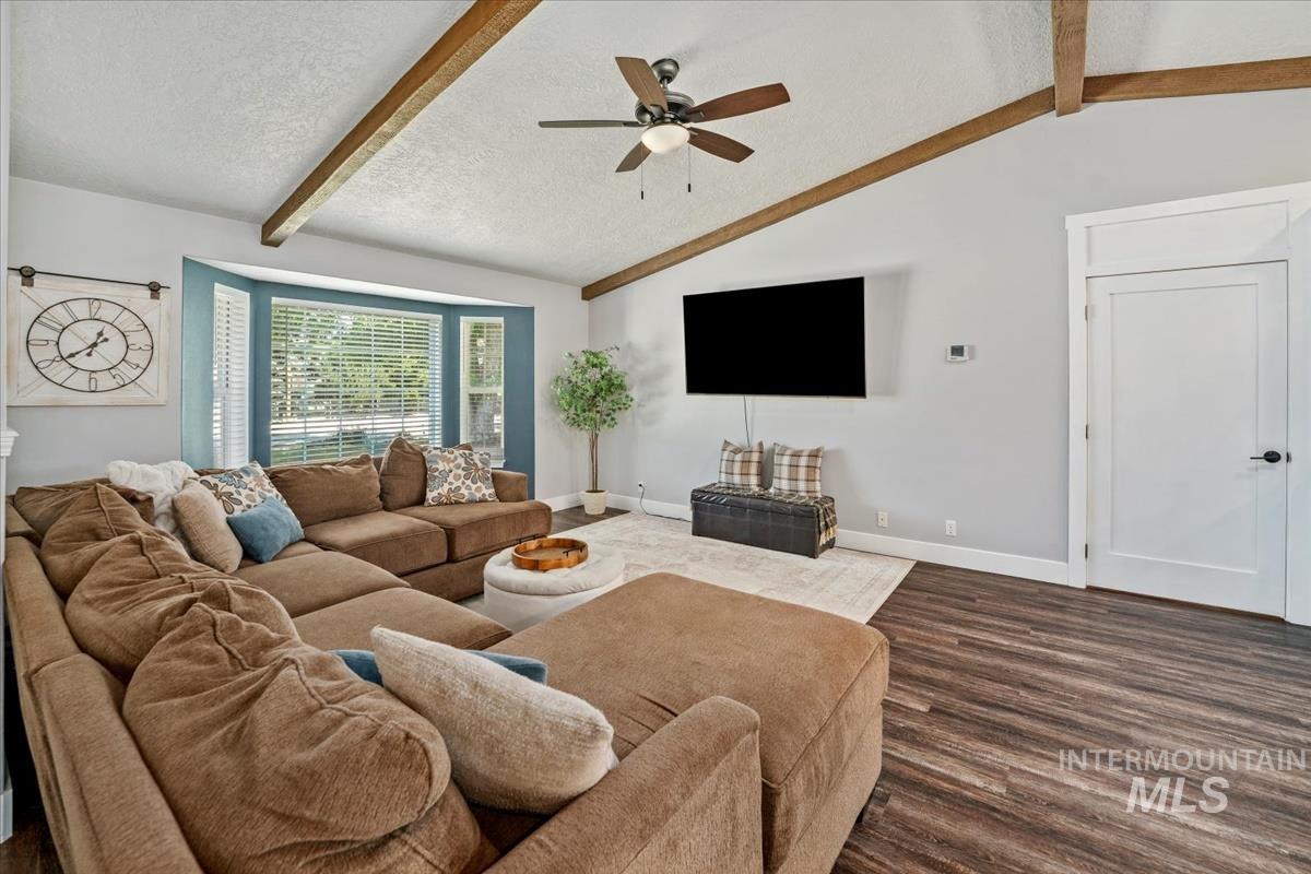 Living room featuring dark wood-style flooring, ceiling fan, and a textured ceiling