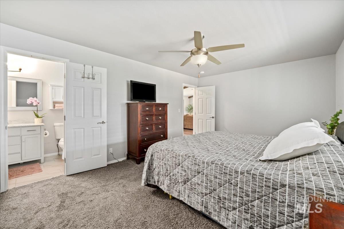 Bedroom with light carpet, ensuite bath, and ceiling fan