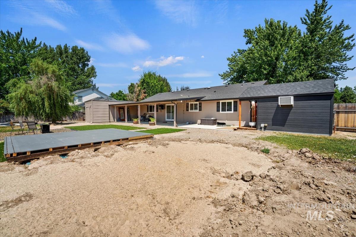 Back of house featuring a patio, a deck, and an outbuilding