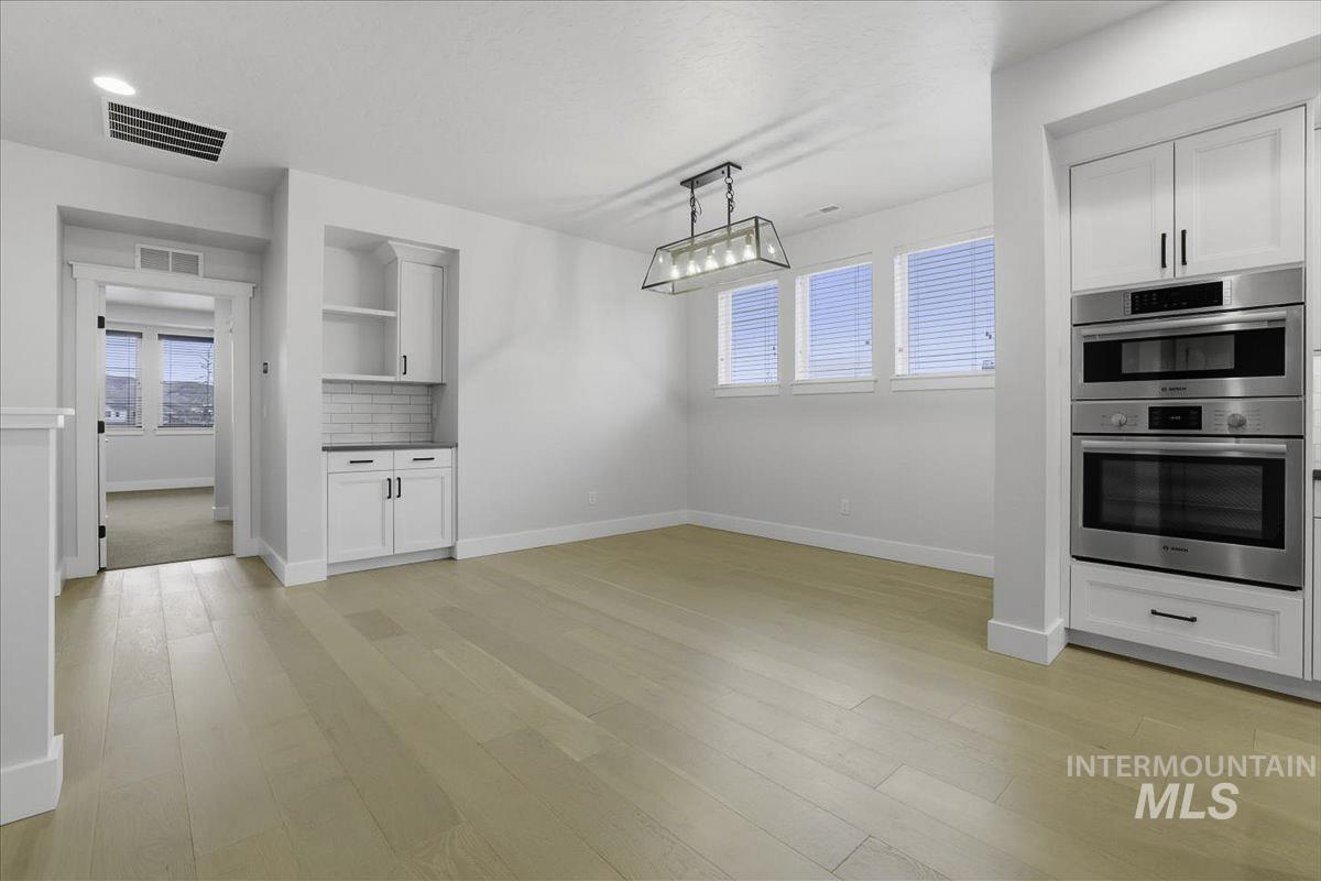 Unfurnished dining area with light wood-style flooring and baseboards