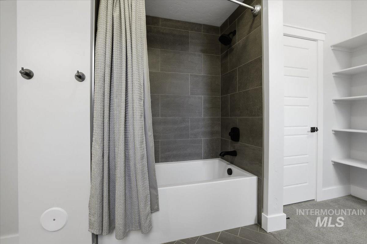 Bathroom featuring shower / bath combination with curtain and carpet flooring