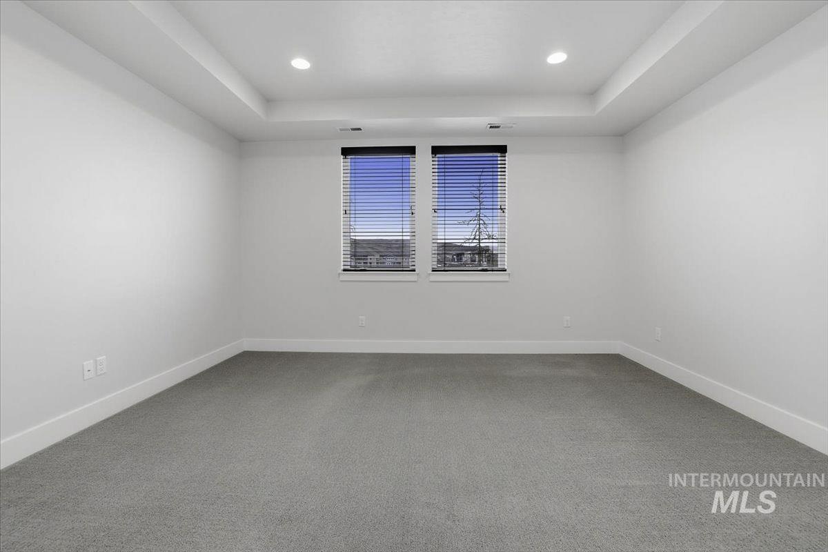 Carpeted spare room with recessed lighting and a tray ceiling