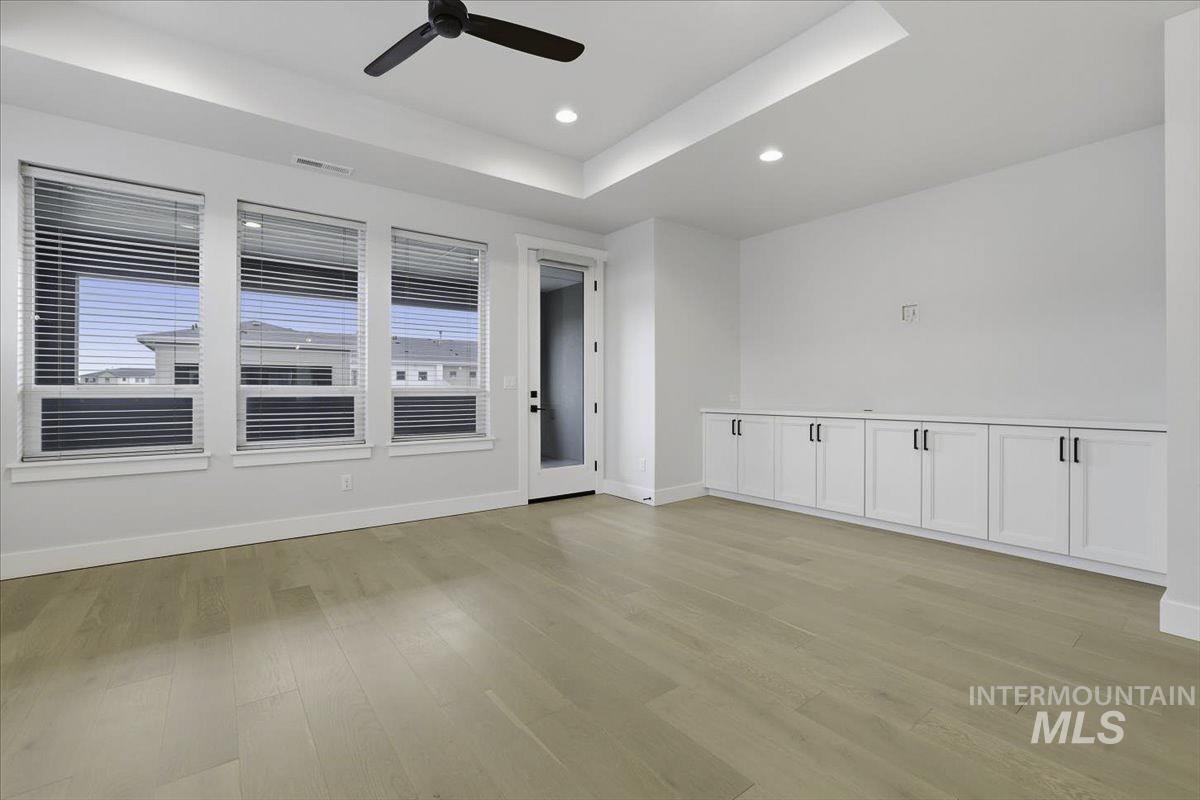Unfurnished room with a raised ceiling, ceiling fan, light wood-style flooring, and recessed lighting