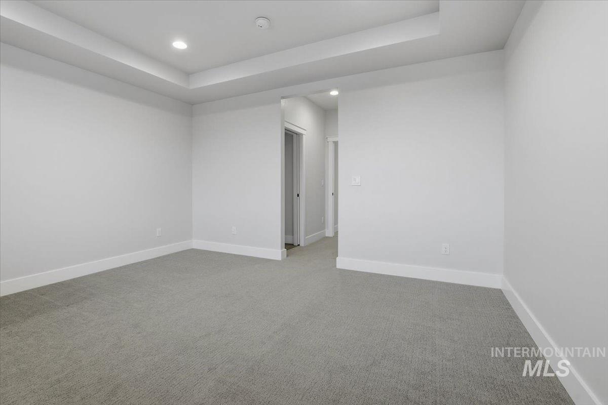 Empty room featuring light colored carpet, recessed lighting, and a raised ceiling