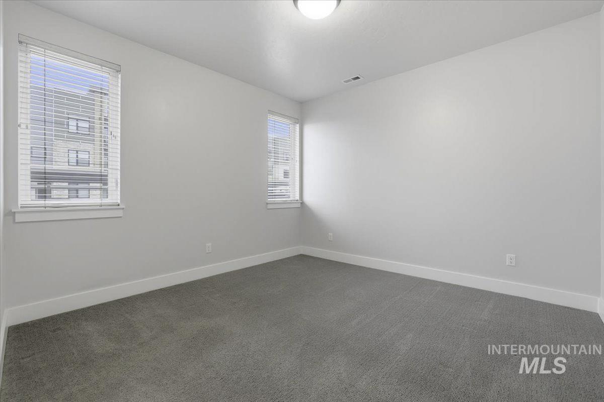 Empty room with dark colored carpet and baseboards