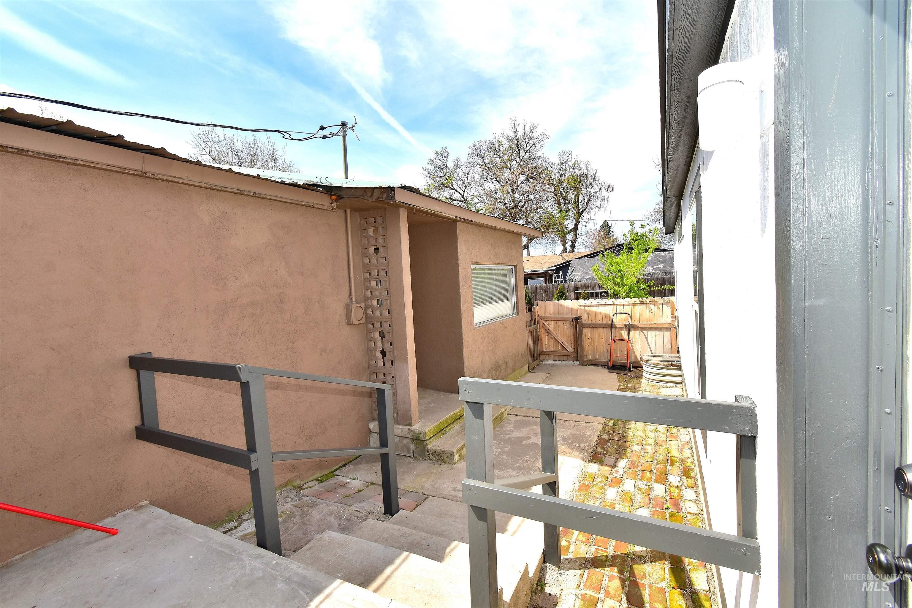 View of home's exterior featuring stucco siding, a gate, and a patio area