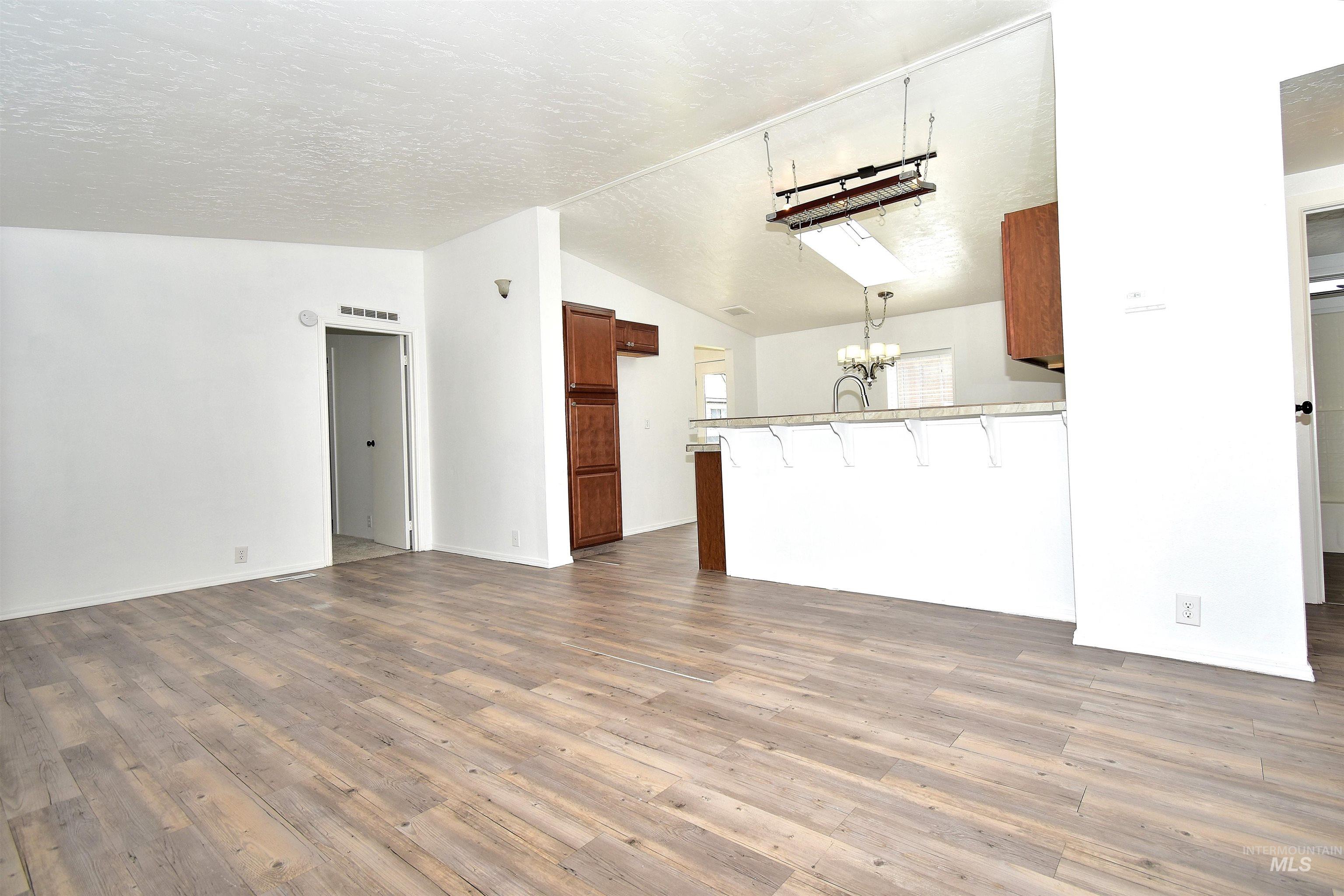 Unfurnished living room with dark wood-style floors and suspended lighting