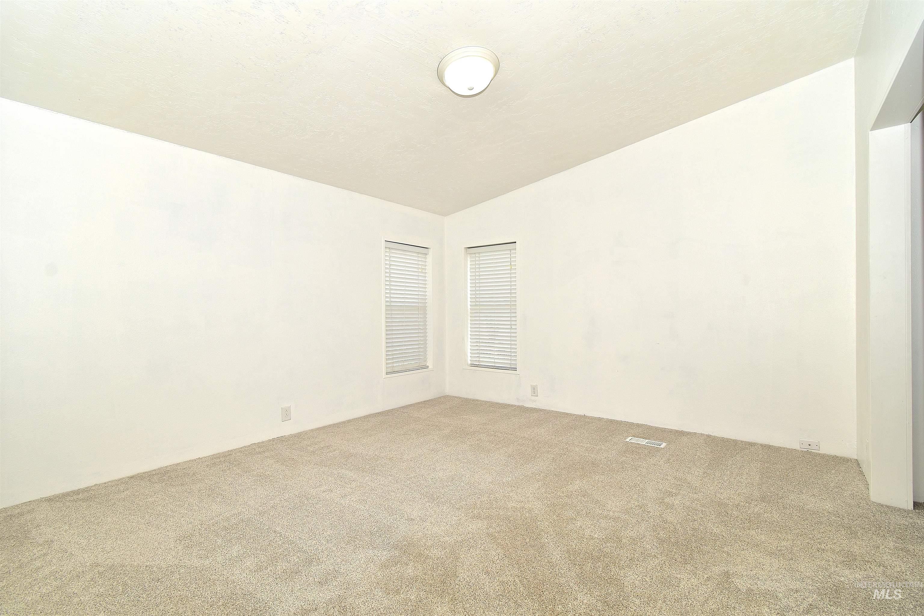 Carpeted empty room featuring vaulted ceiling