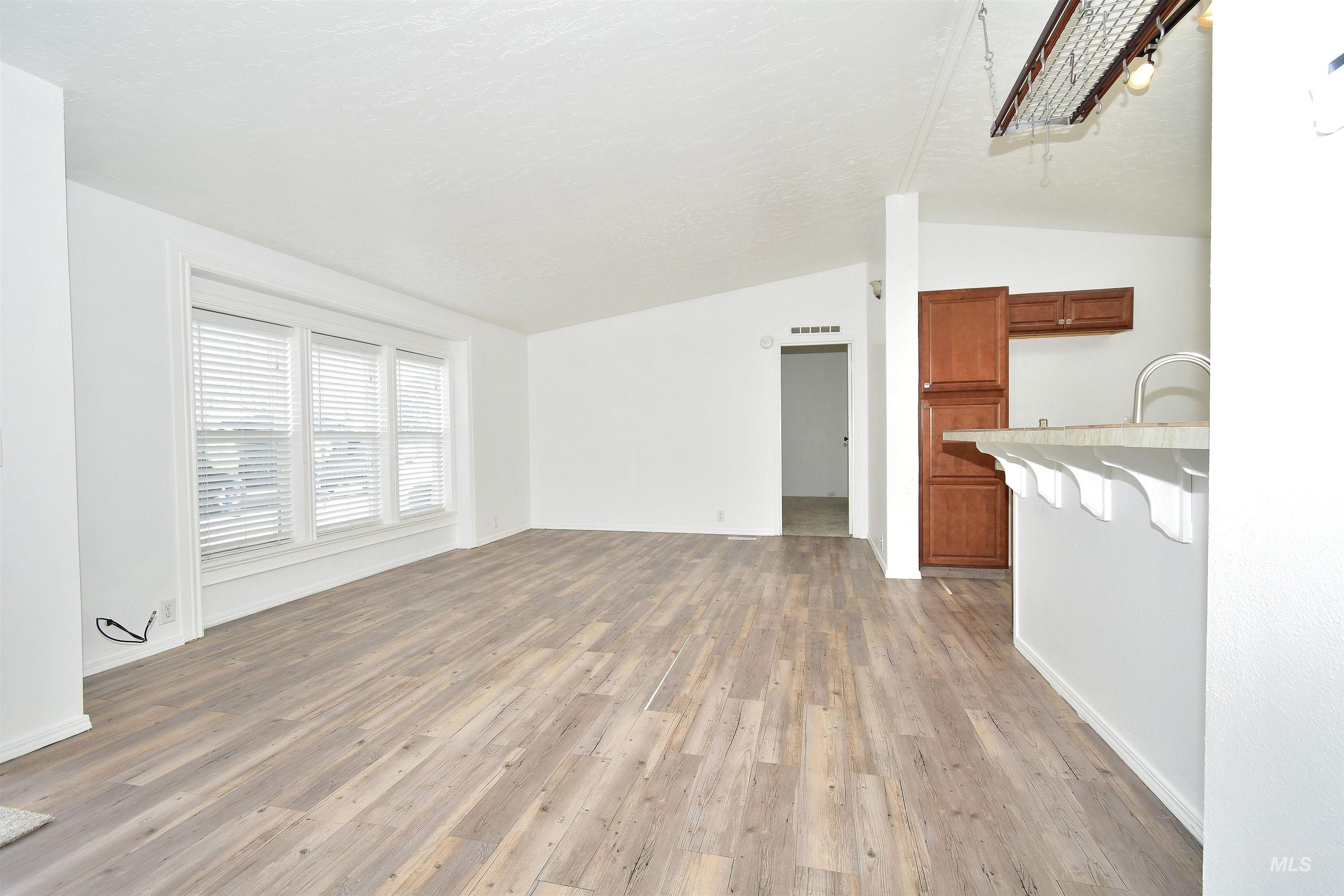 Unfurnished living room with lofted ceiling and light wood-type flooring