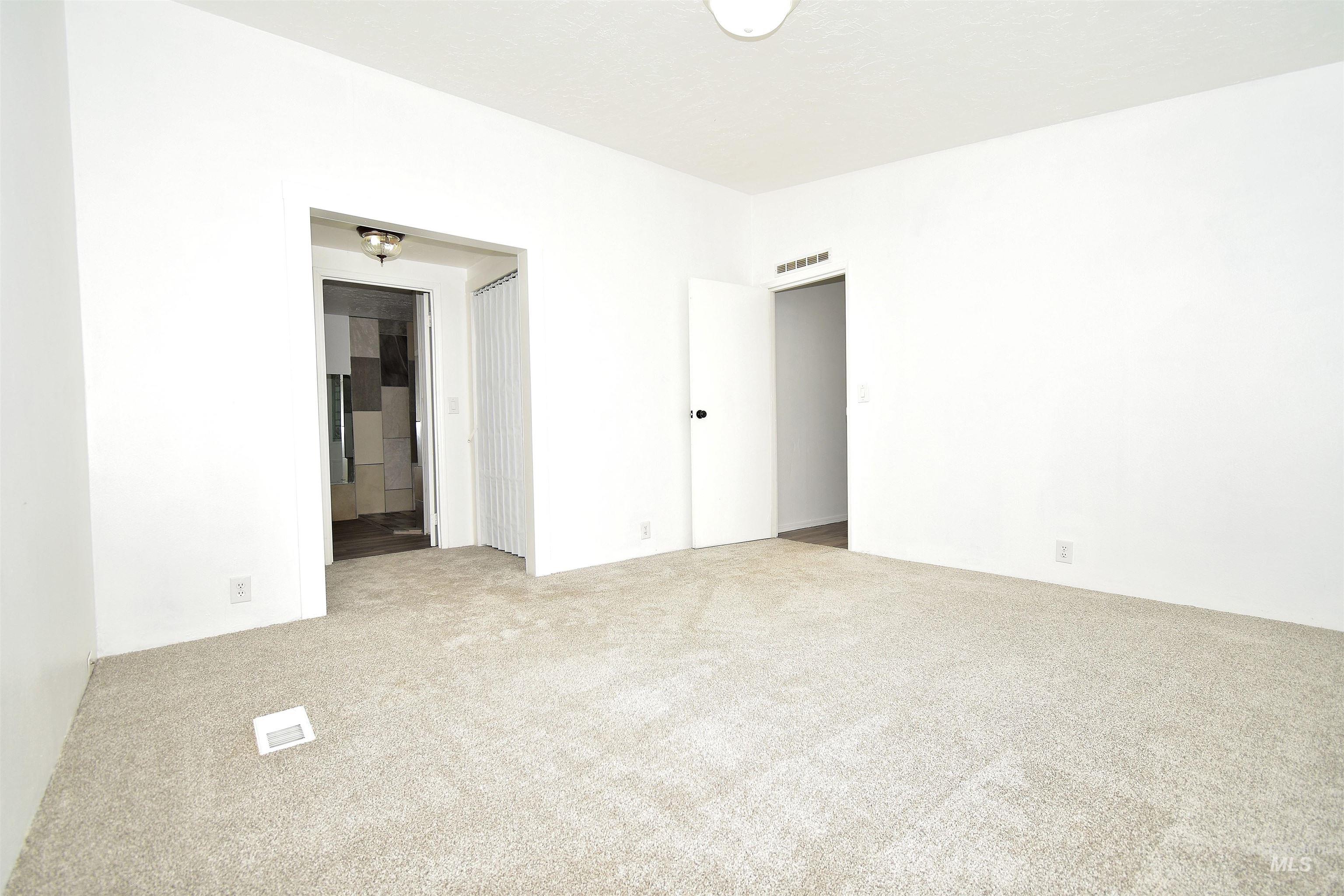 Unfurnished bedroom with light carpet and ensuite bathroom