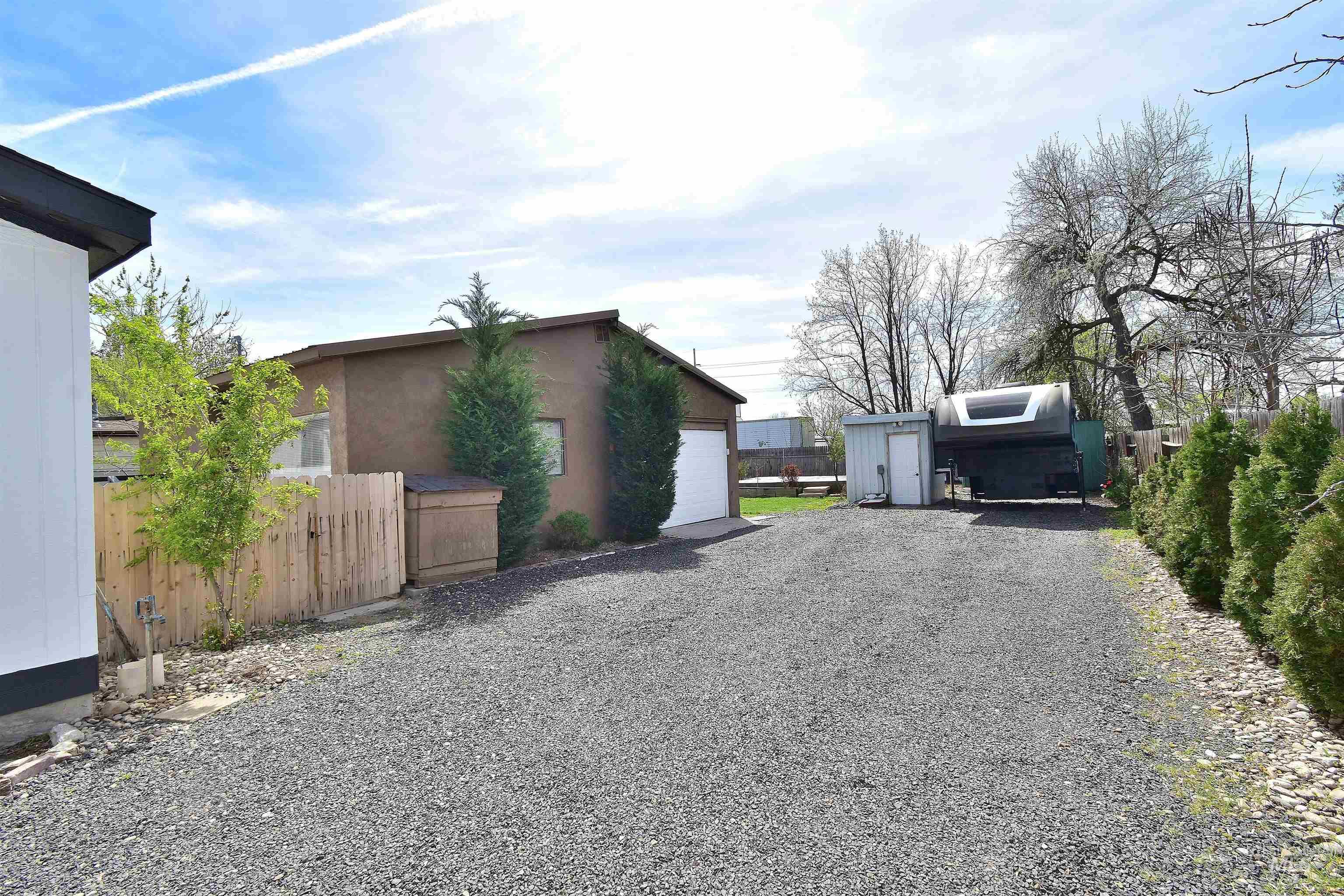 View of property exterior with an outdoor structure, stucco siding, a garage, and gravel driveway