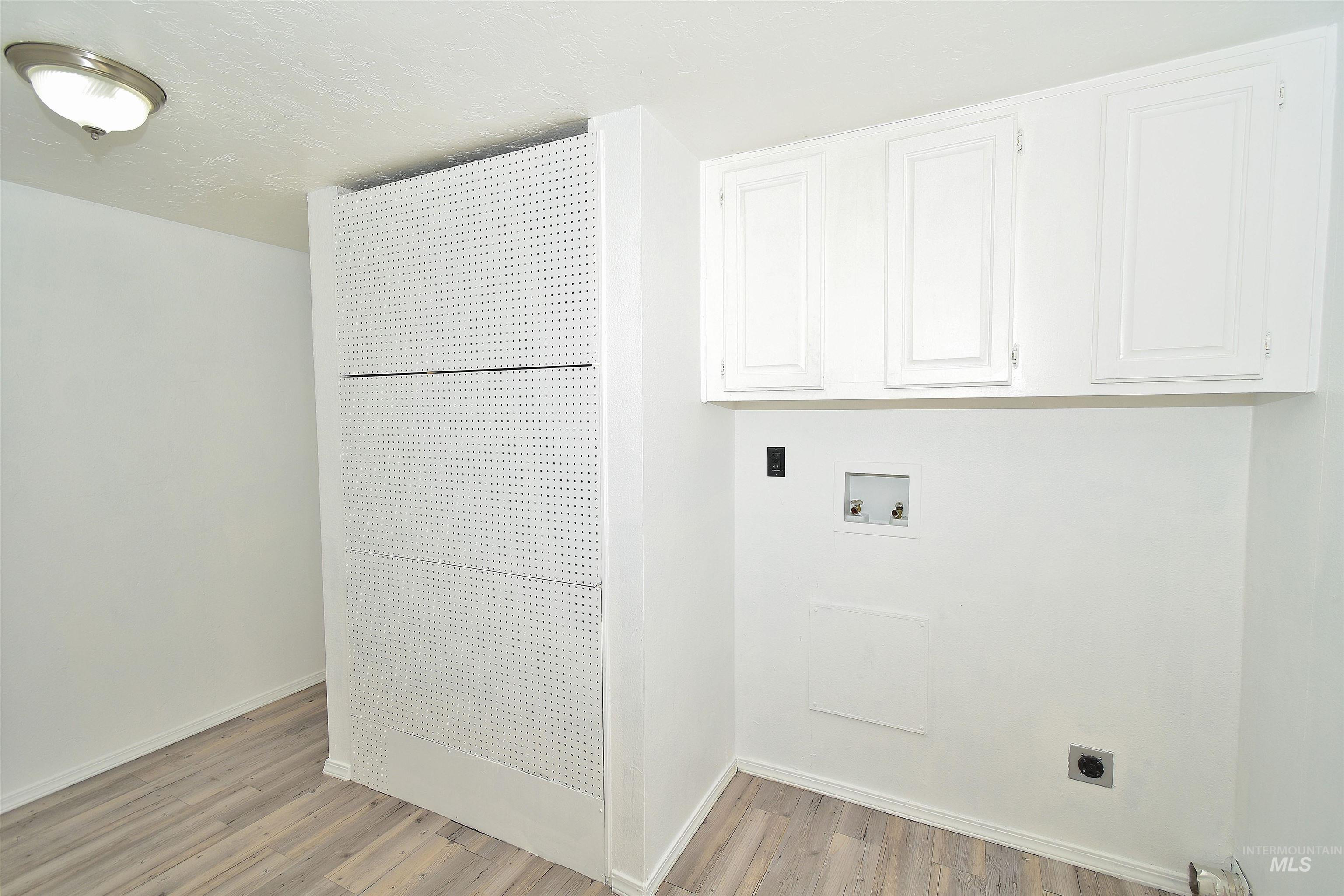 Laundry room with electric dryer hookup, light wood finished floors, hookup for a washing machine, and cabinet space