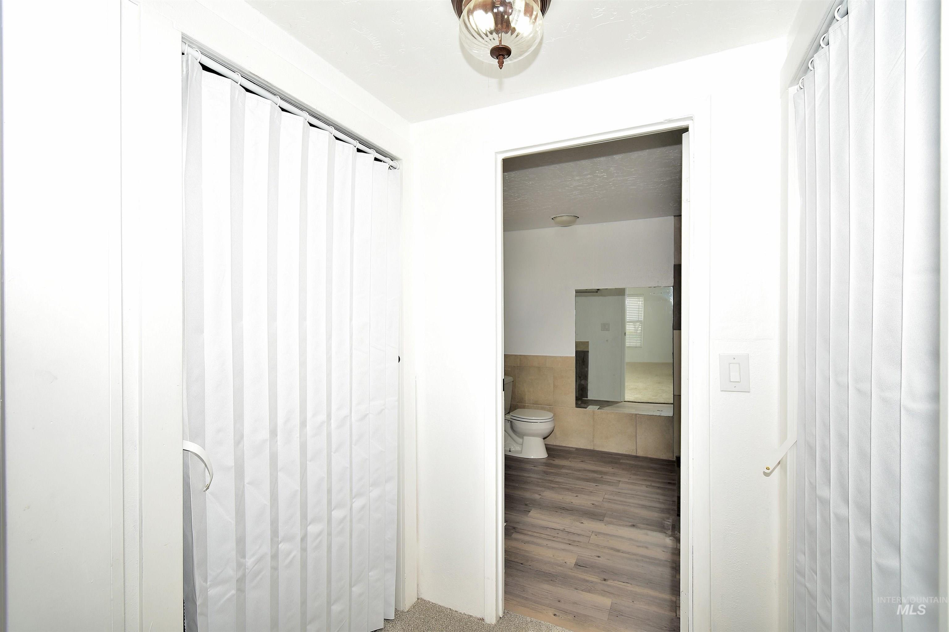 Bathroom with tile walls, a textured ceiling, wood finished floors, and wainscoting