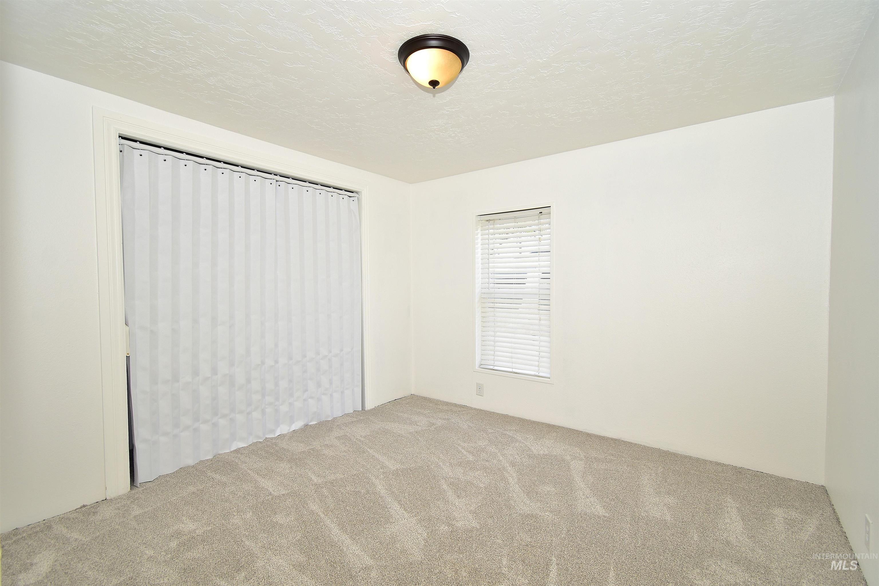 Empty room featuring a textured ceiling and light colored carpet