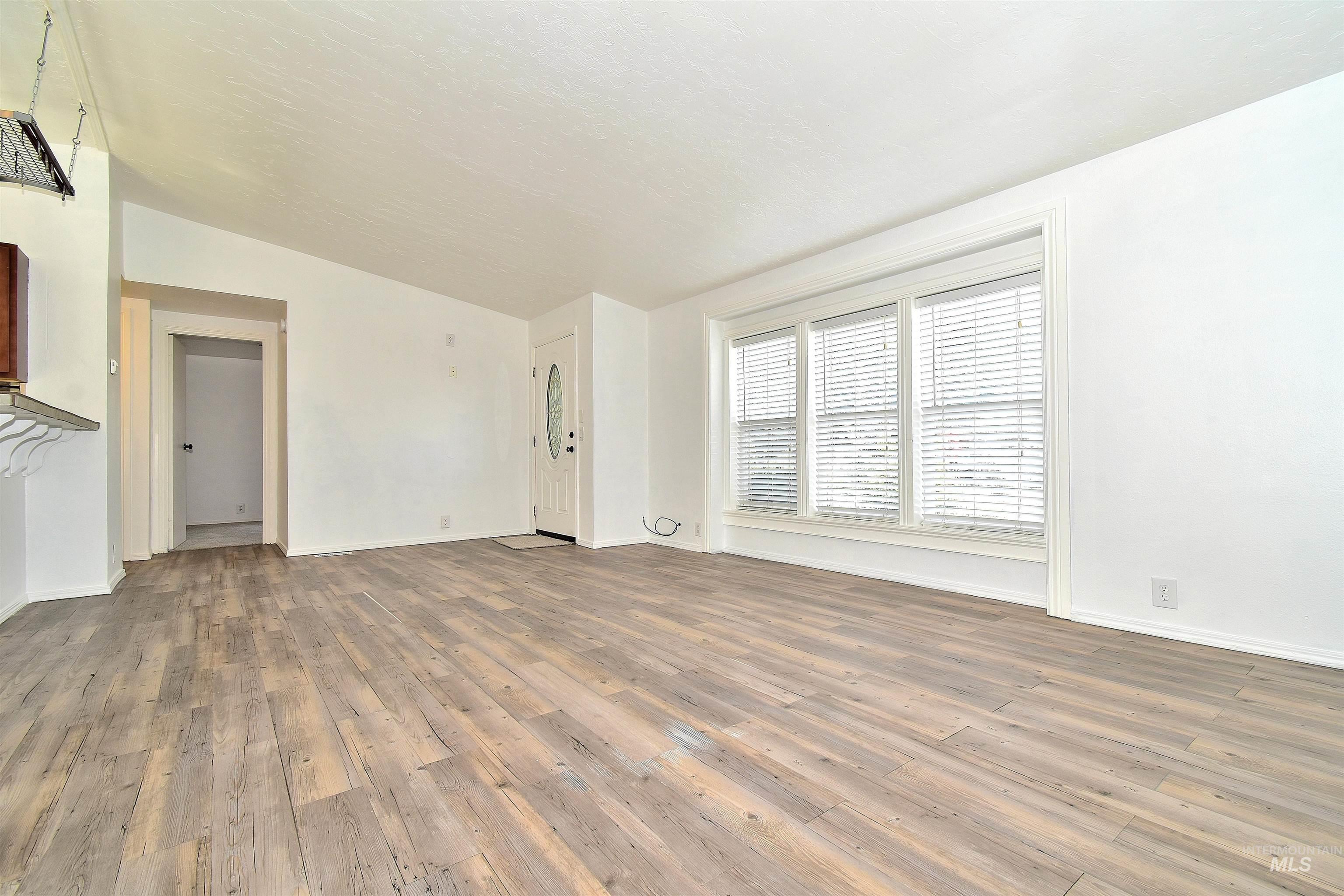 Unfurnished living room featuring wood finished floors and vaulted ceiling