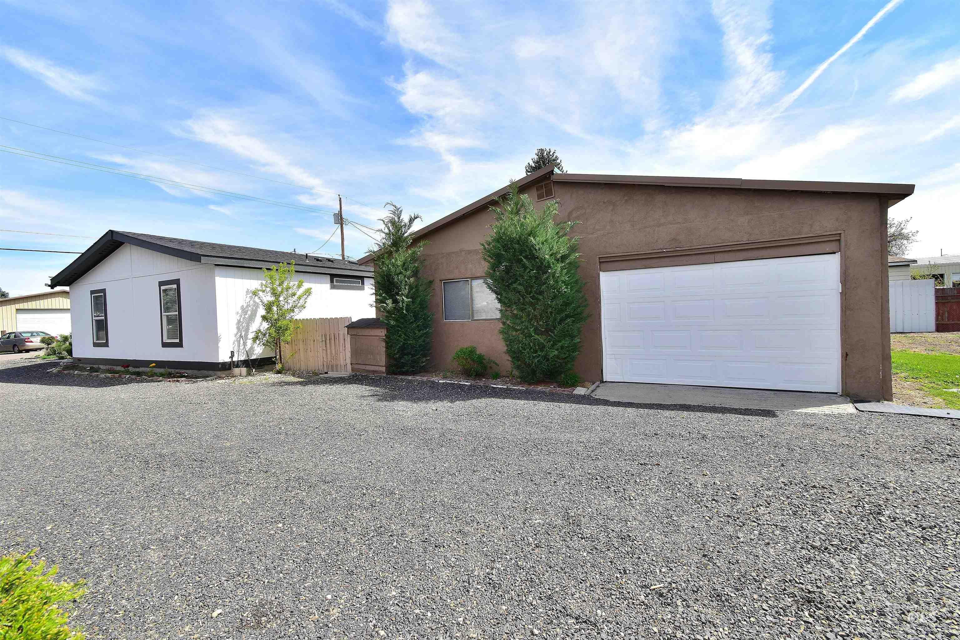 View of property exterior with a garage, stucco siding, driveway, and an outbuilding