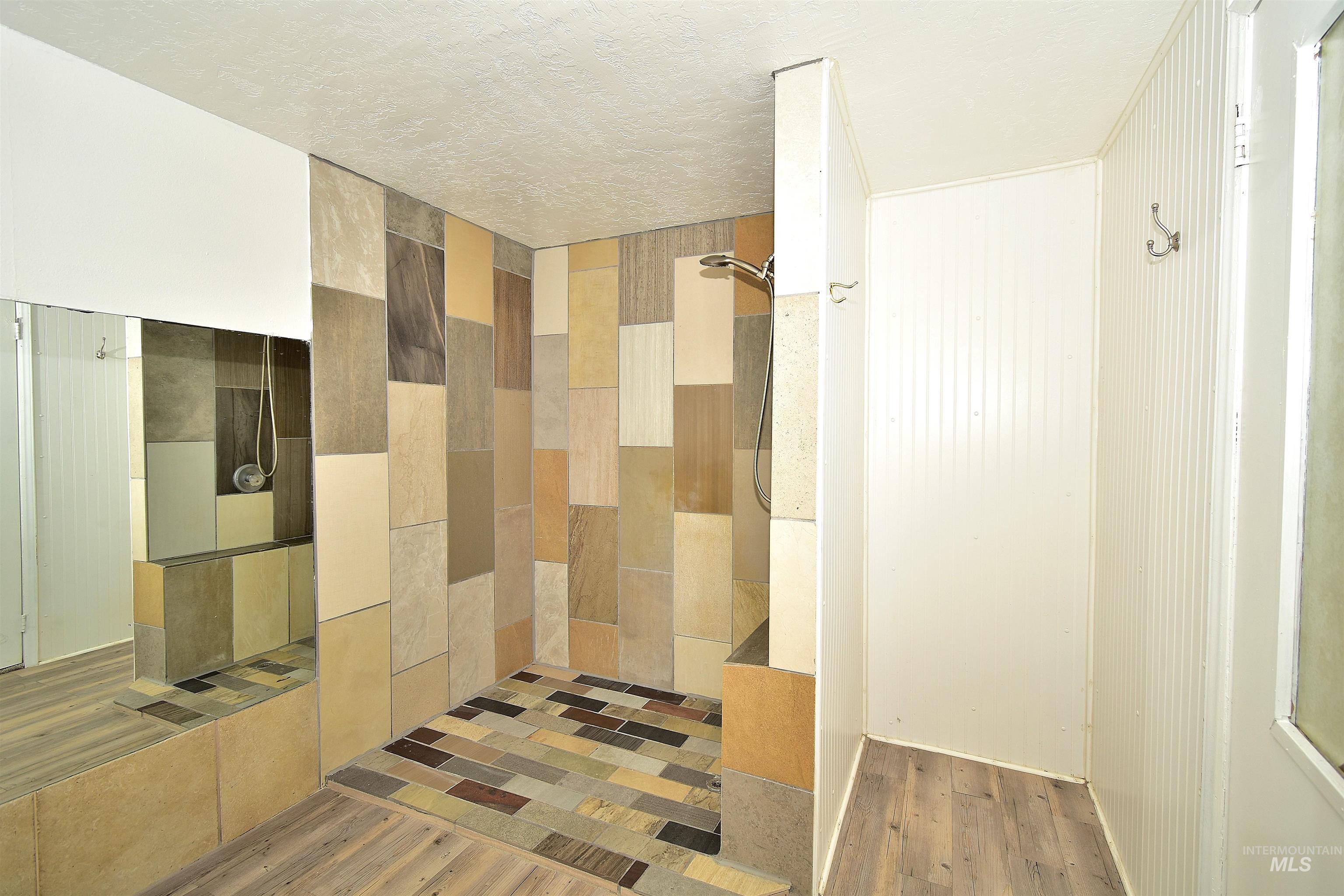Bathroom featuring a walk in shower, light wood finished floors, and a textured ceiling