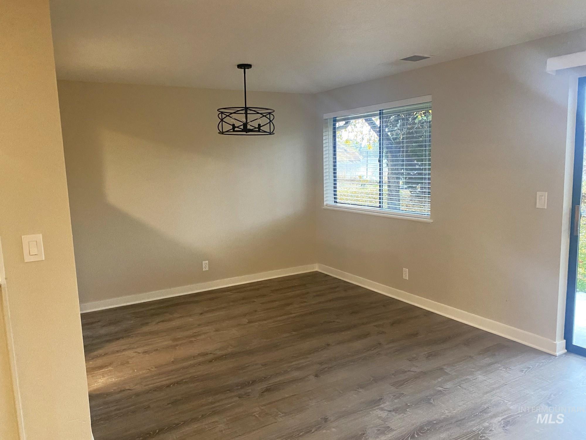 Unfurnished room featuring dark wood-type flooring and baseboards