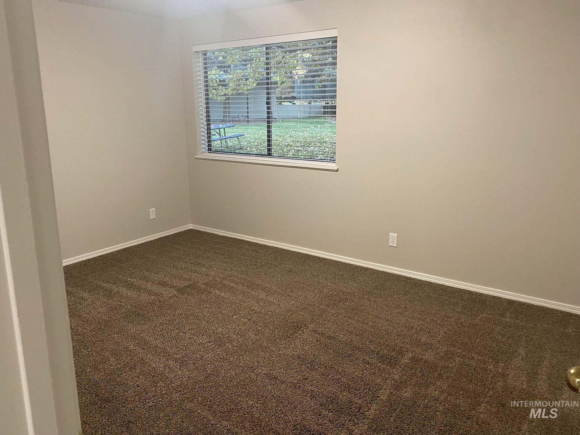 Spare room with dark colored carpet and baseboards