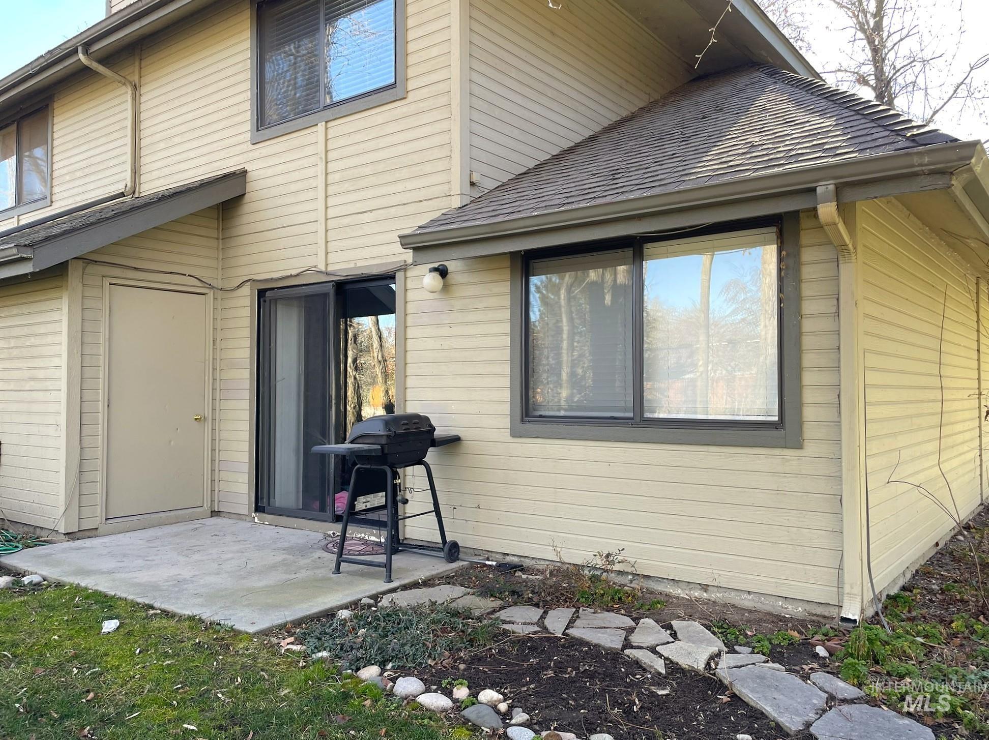 Rear view of property featuring roof with shingles and a patio area