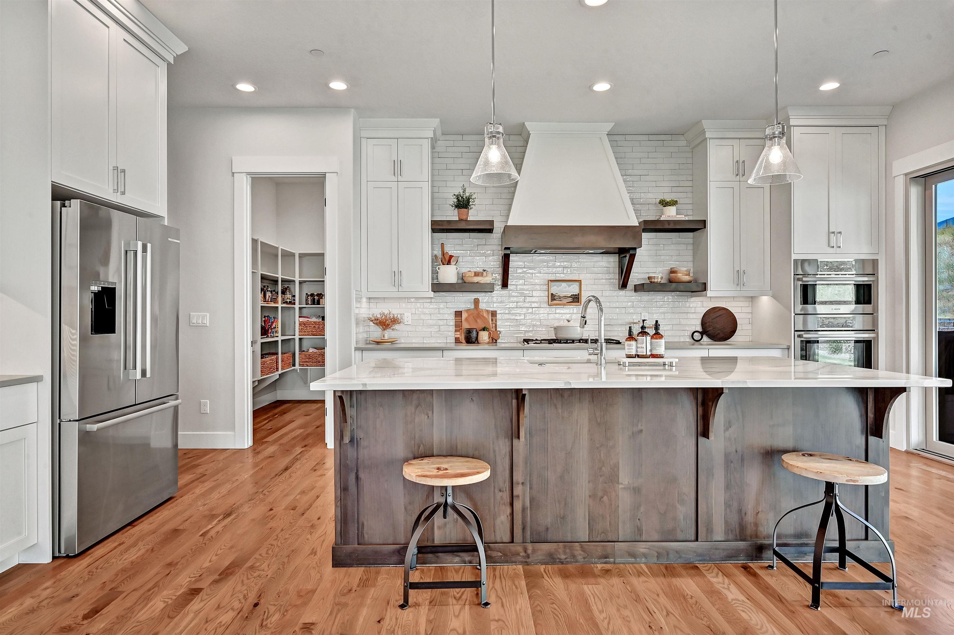 Kitchen featuring stainless steel appliances, open shelves, a breakfast bar area, white cabinets, and backsplash