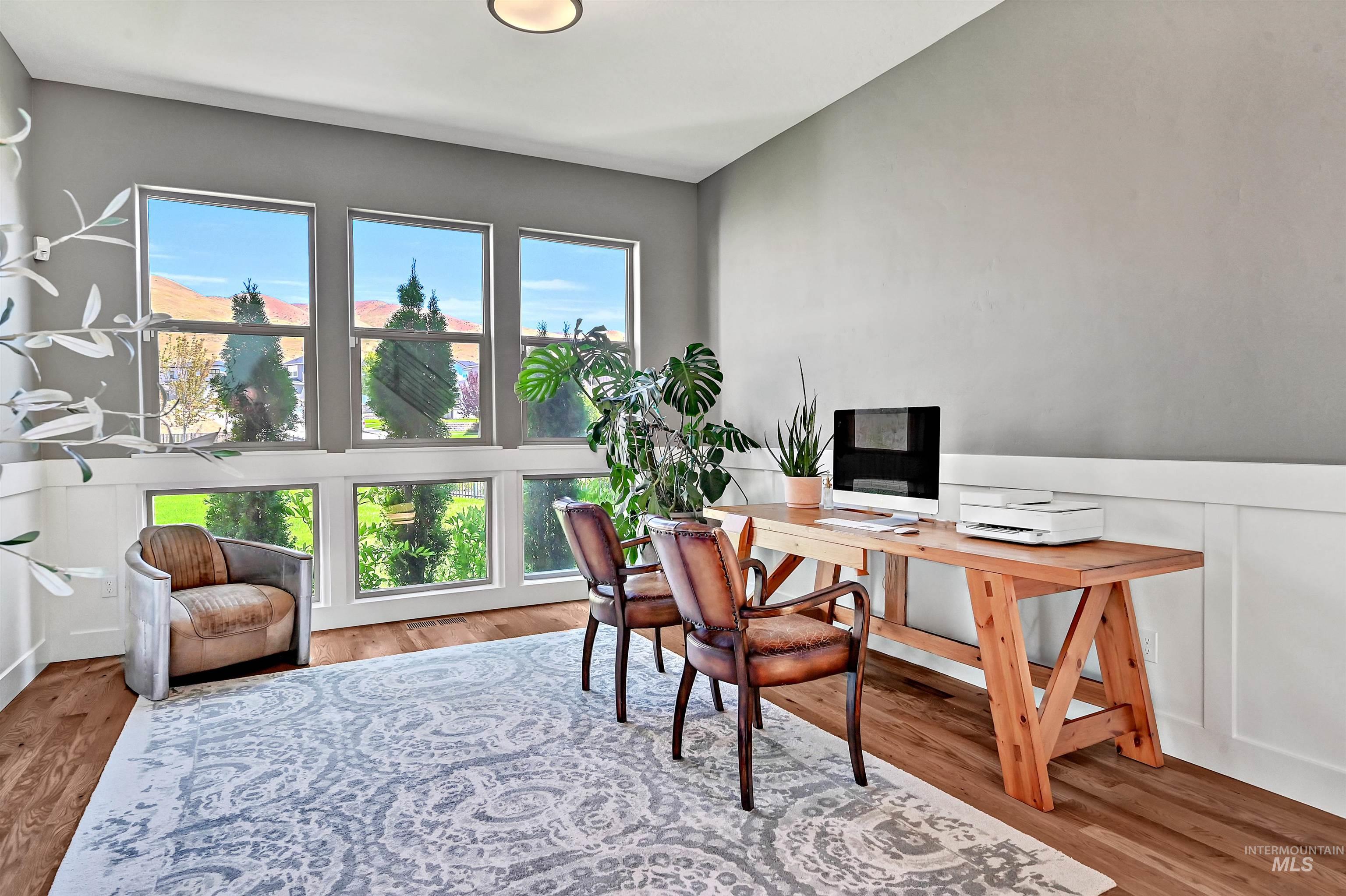 Office space featuring light wood-type flooring, wainscoting, and a decorative wall