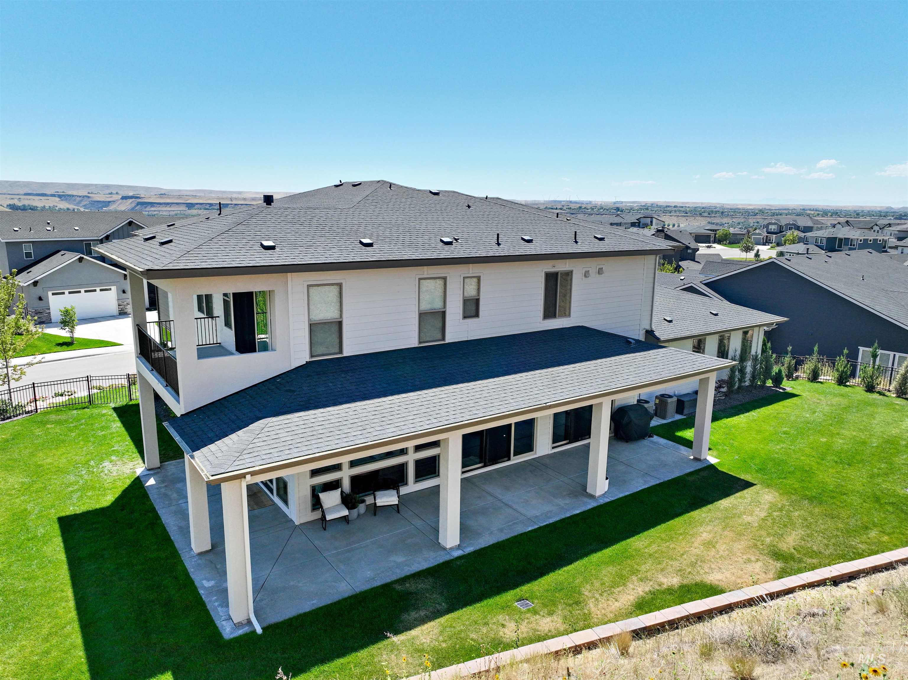 Back of house featuring a patio area and roof with shingles