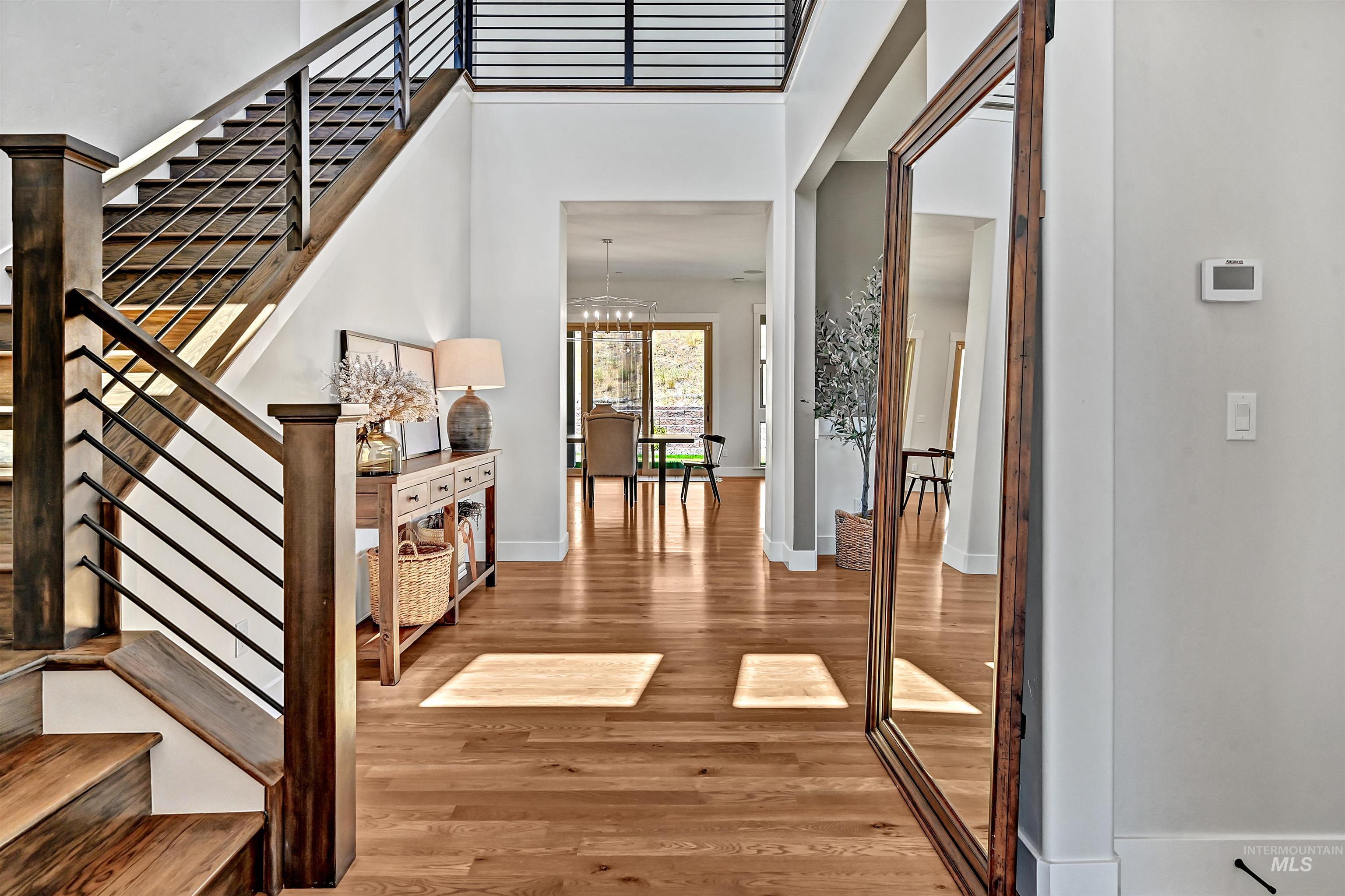 Entryway featuring stairway, light wood-style flooring, a chandelier, and a high ceiling